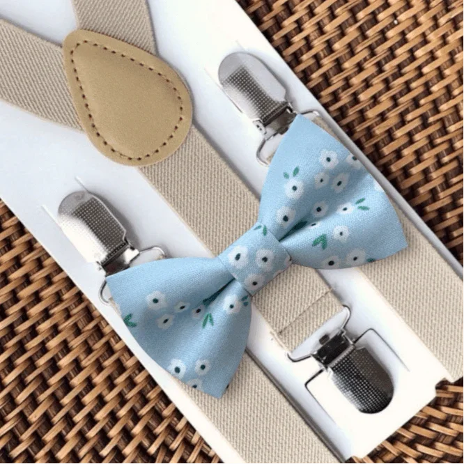 Floral dusty blue bow tie paired with tan suspenders and metal clips.