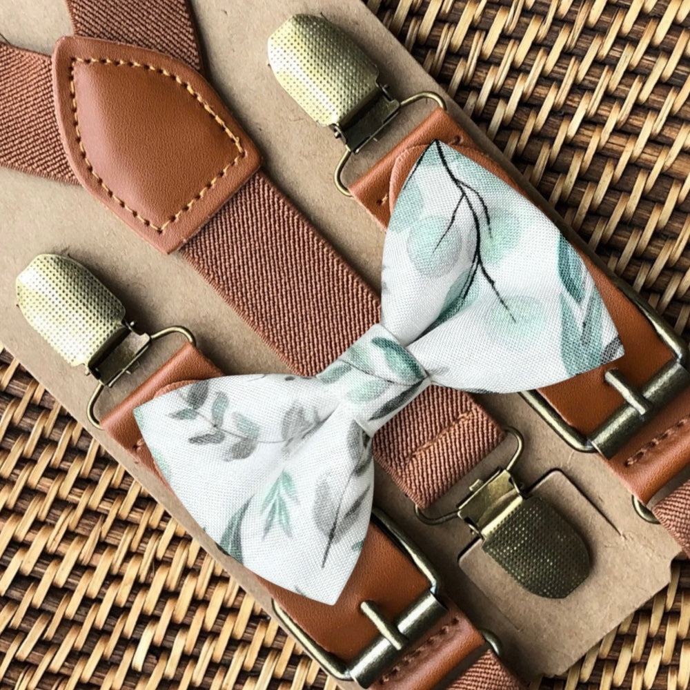 Floral bow tie with brown suspenders on a woven surface for groomsmen and ring bearers for wedding.