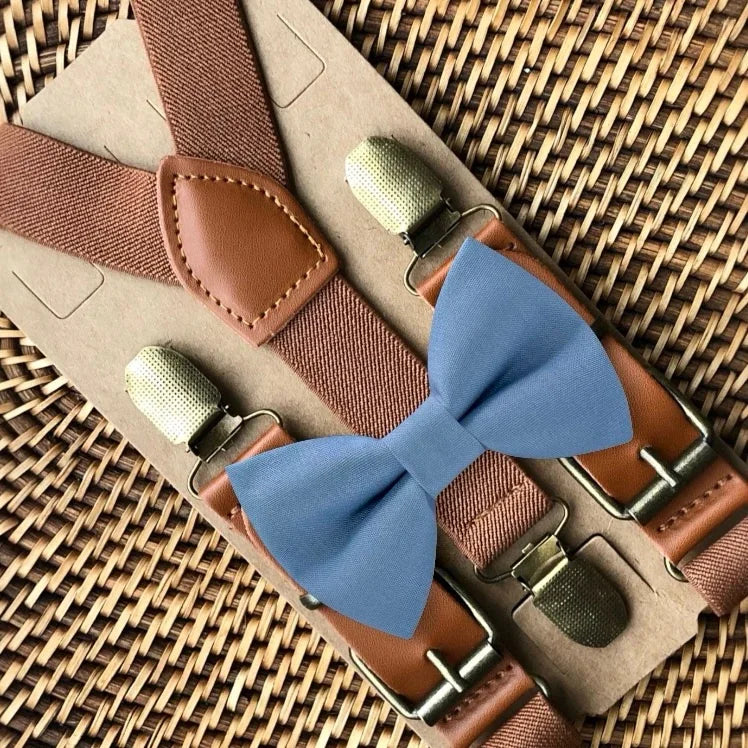 Dusty blue bow tie with brown suspenders on a woven surface