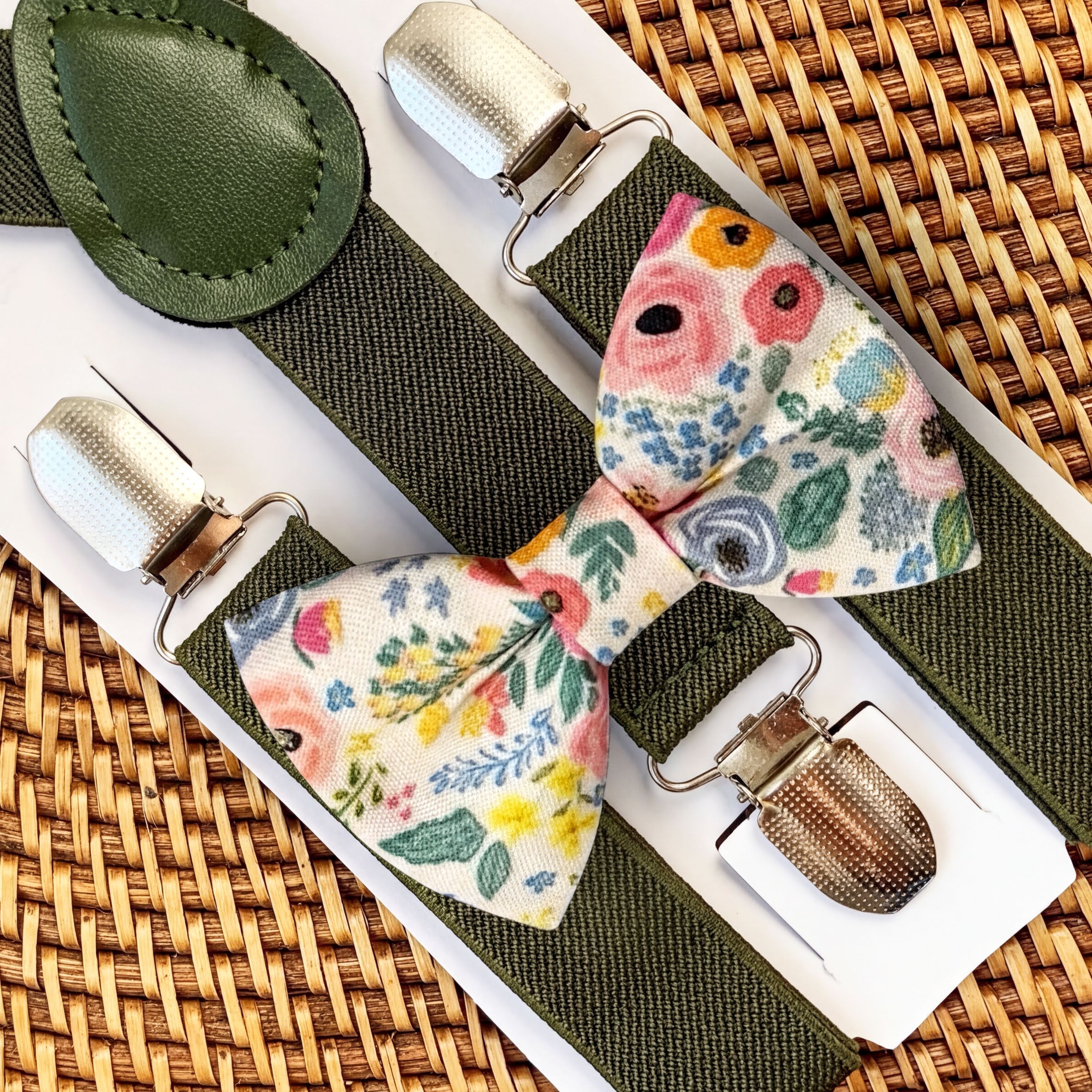 Floral bow tie and suspenders set for a wedding, groomsmen or ring bearer on a woven surface