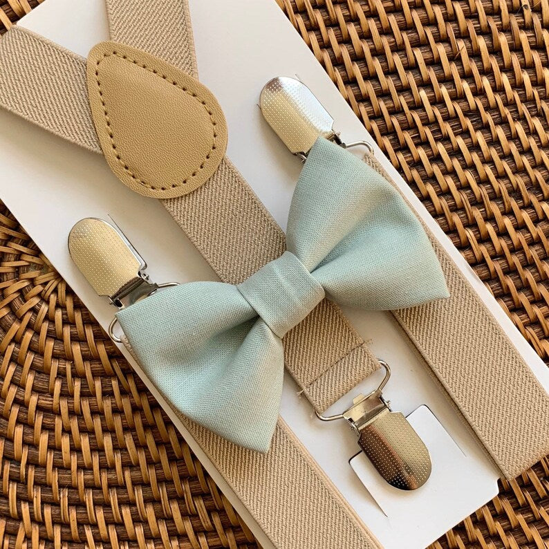 Sage Bow Tie & Tan Suspenders Set for wedding groomsmen, groom and ring bearers on a brown woven tray.