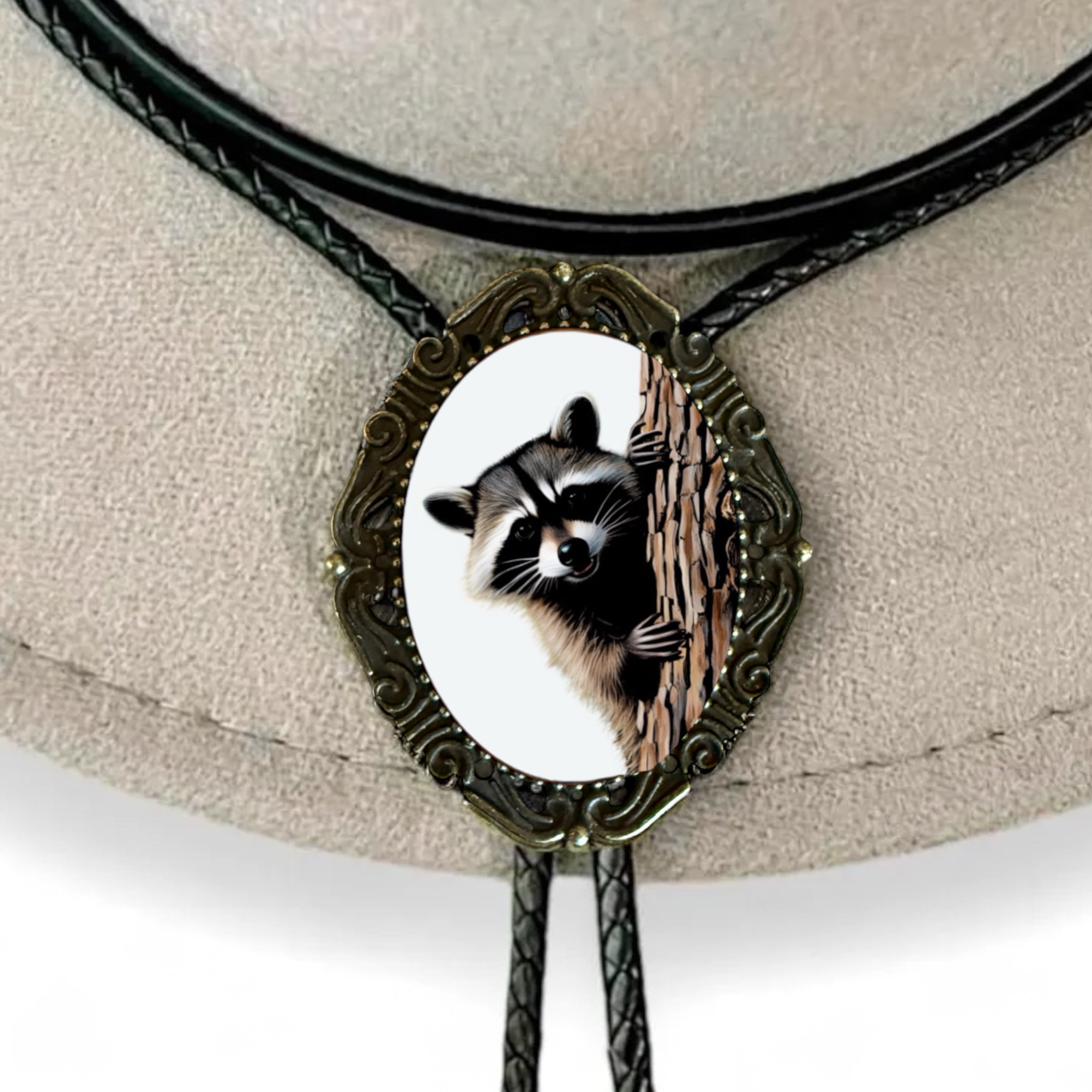 Western Bolo Tie with Raccoon with black leather cord on a wooden table.
