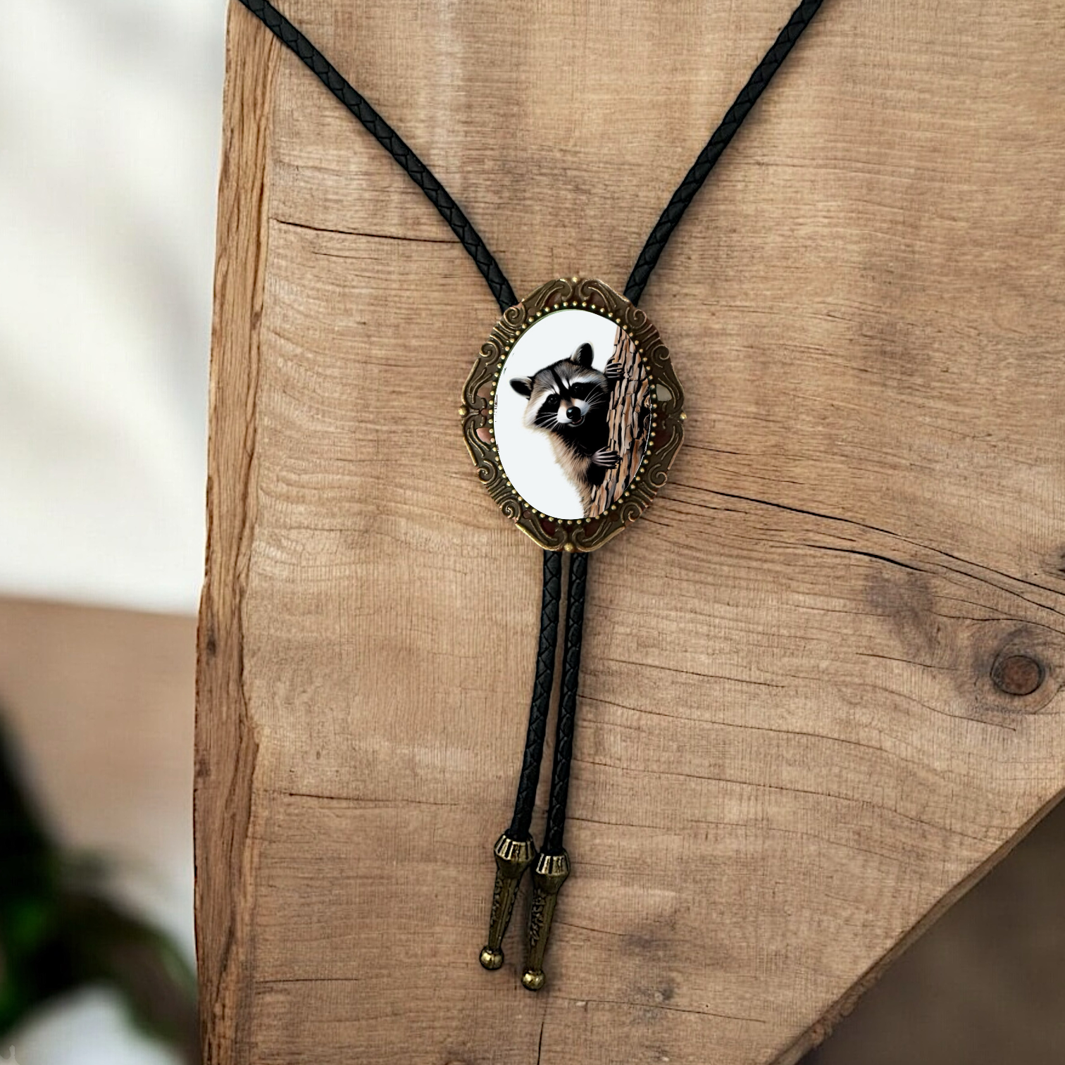 Western Bolo Tie with Raccoon with black leather cord on a wooden wall.