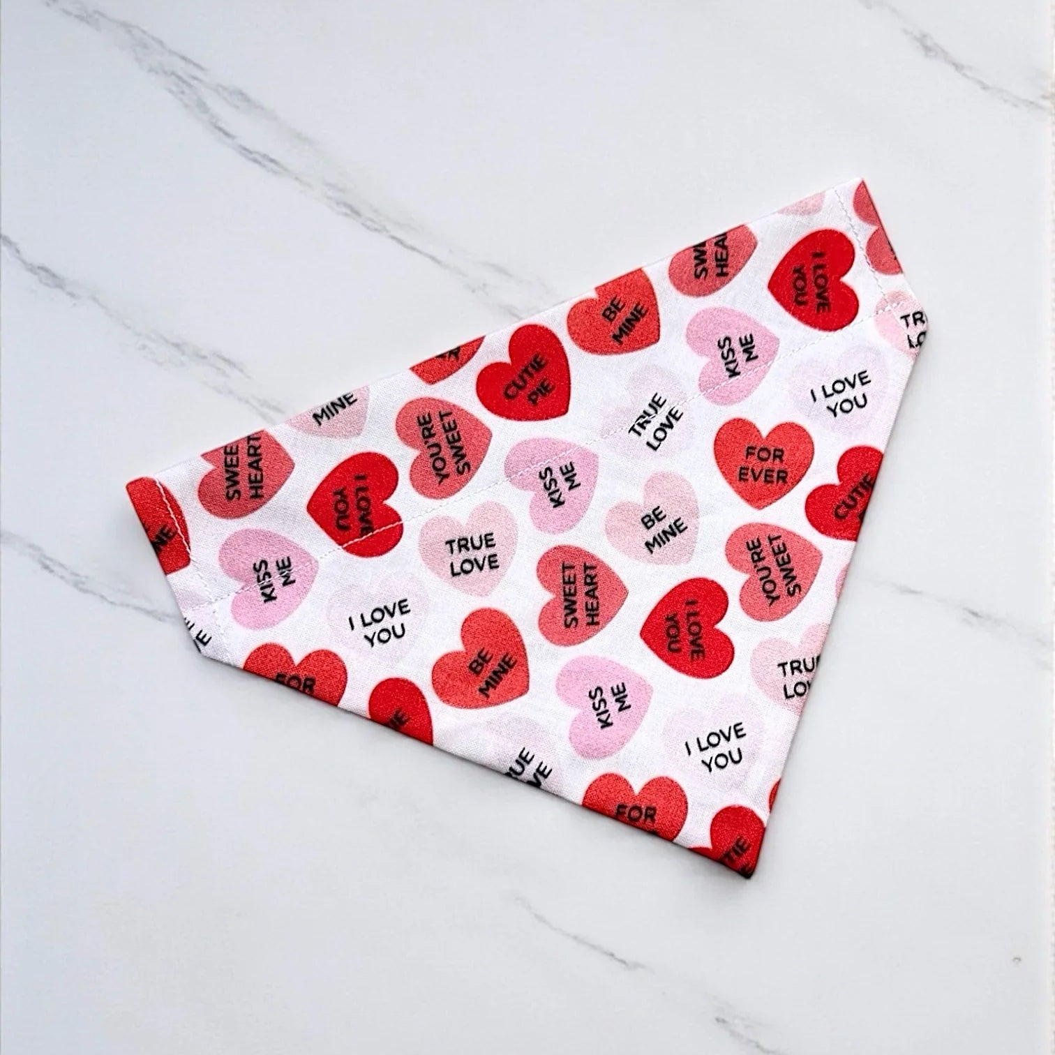 Heart-shaped dog bandana on a white tiled floor