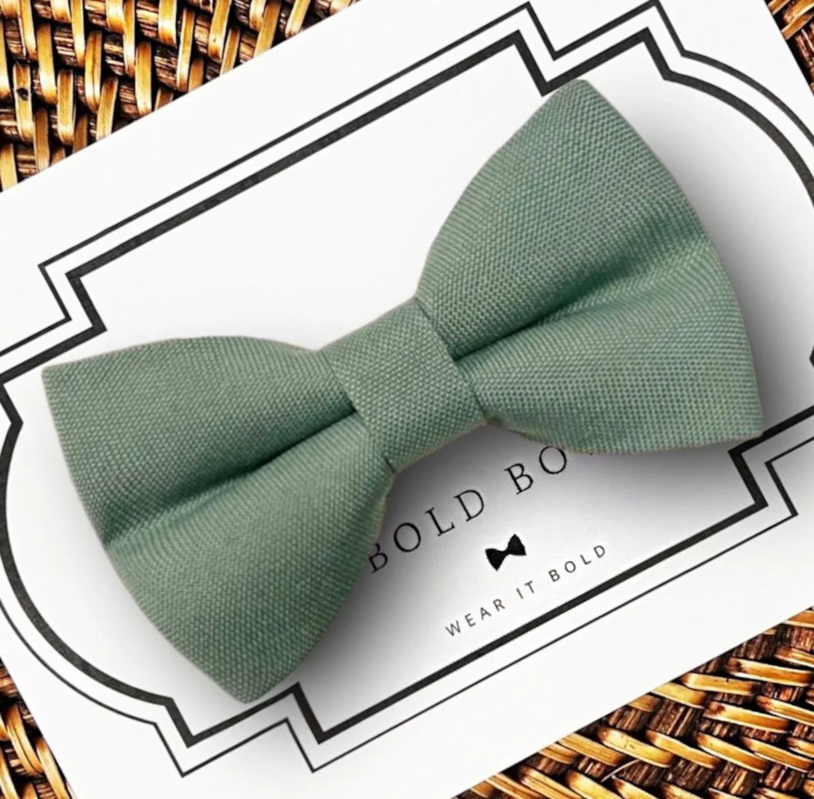 Product graphic showcasing the back of a pre-tied bow tie in a red and black buffalo plaid pattern, resting on a rustic wood surface. Two black elastic loops are attached to the center knot to slide onto a pet collar. Overlay text reads: Back of Bow Tie (may not be actual bow tie in listing).