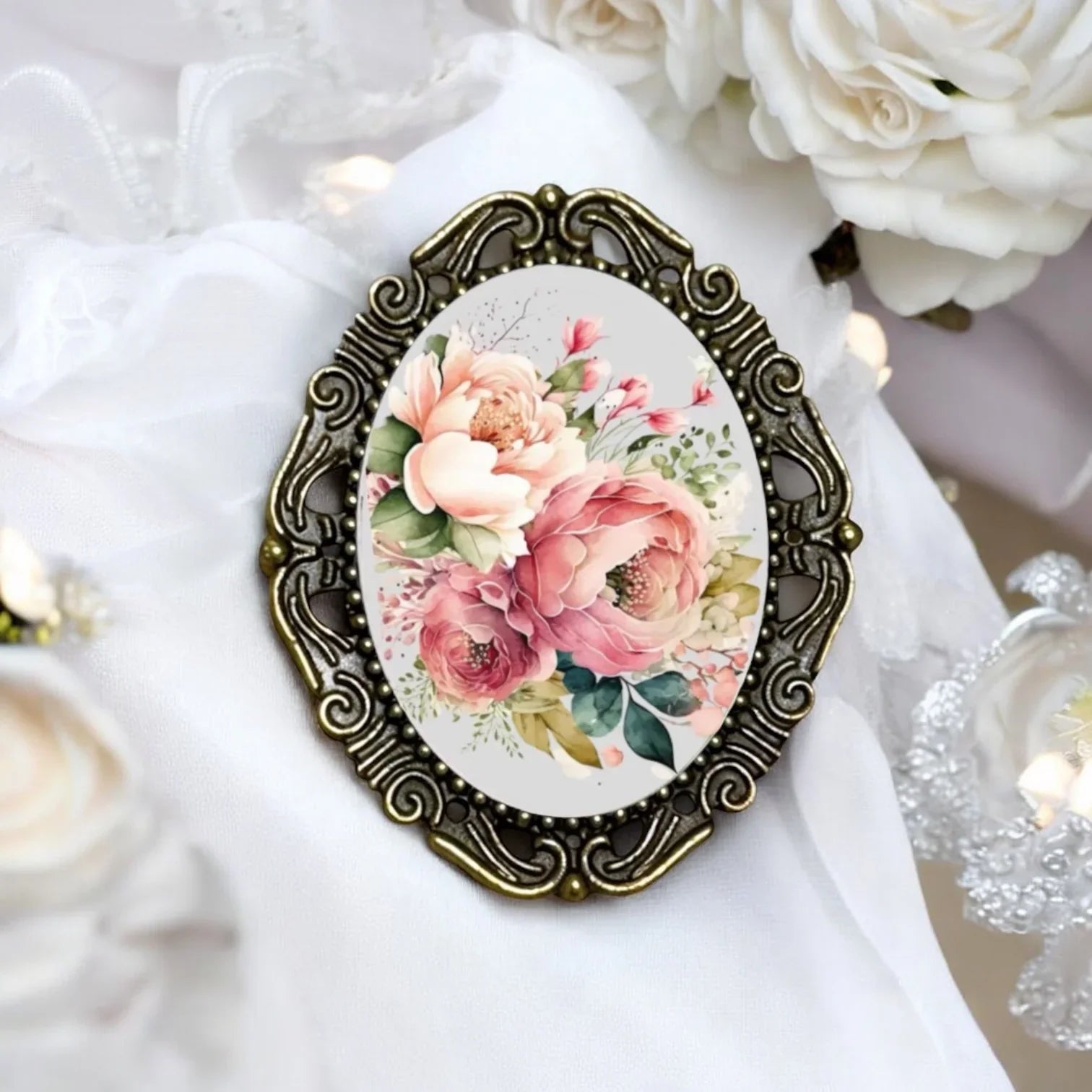 Decorative brooch with floral design in an ornate bronze frame on a white fabric background.