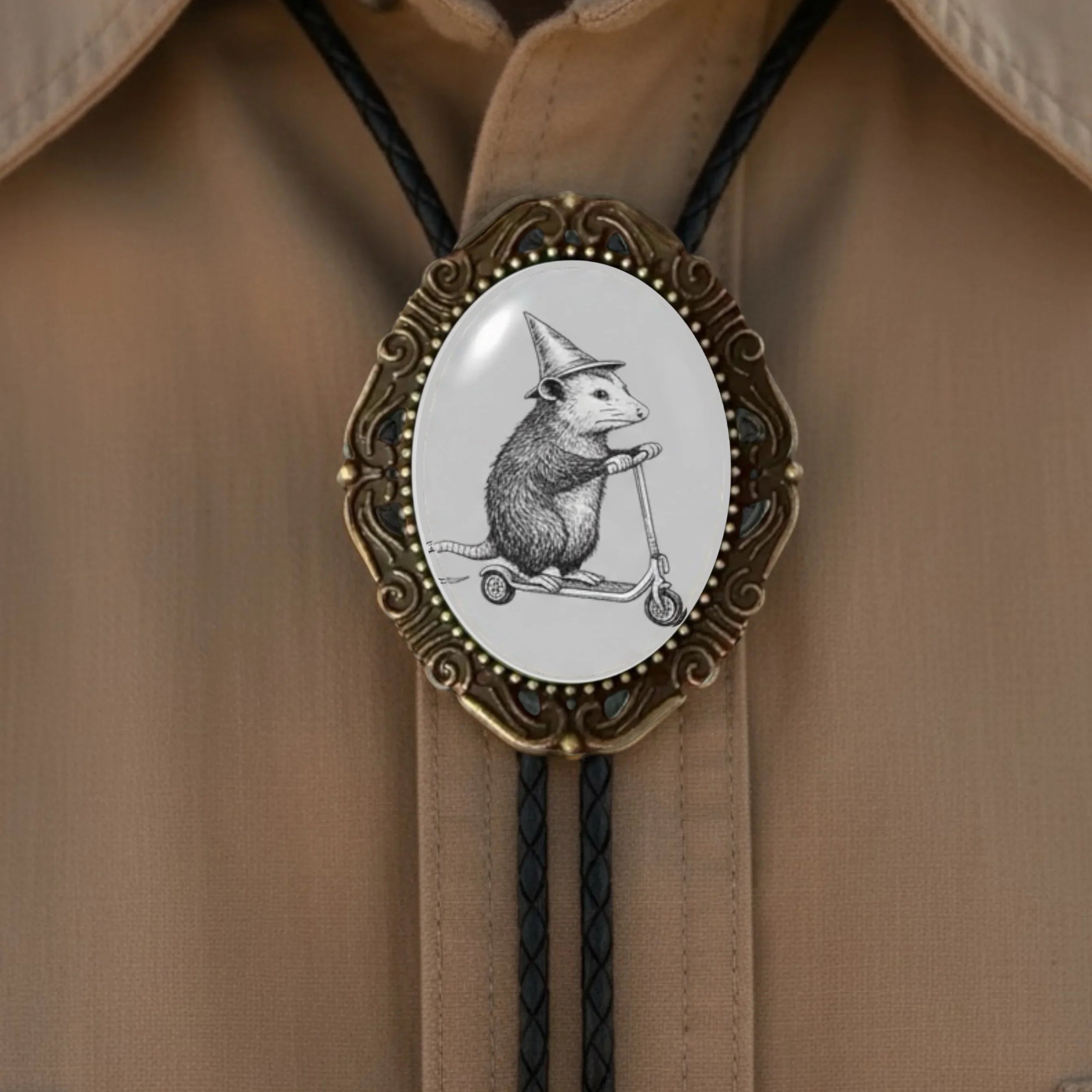Bolo tie size chart from The Bold Bow Tie. The image displays a braided leather bolo tie with a round silver concho-style slide and silver metal tips, set against a multi-colored striped fabric background. A vertical dotted arrow on the right spans the full length of the piece, accompanied by text indicating a 39 inch cord length.