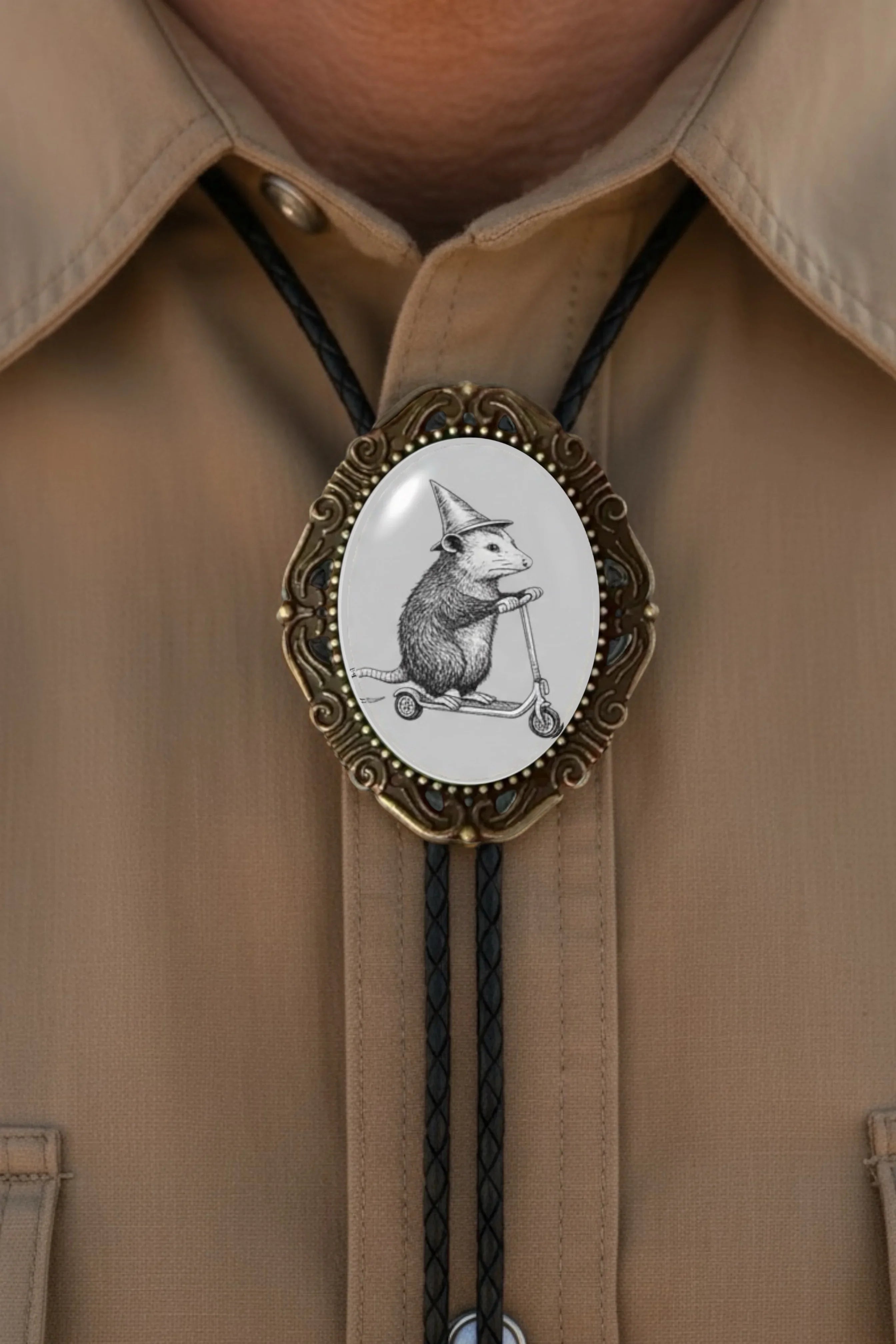 Bolo tie size chart from The Bold Bow Tie. The image displays a braided leather bolo tie with a round silver concho-style slide and silver metal tips, set against a multi-colored striped fabric background. A vertical dotted arrow on the right spans the full length of the piece, accompanied by text indicating a 39 inch cord length.