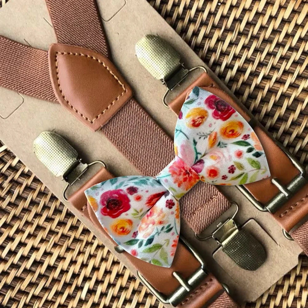 Floral bow tie with brown suspenders on a woven surface