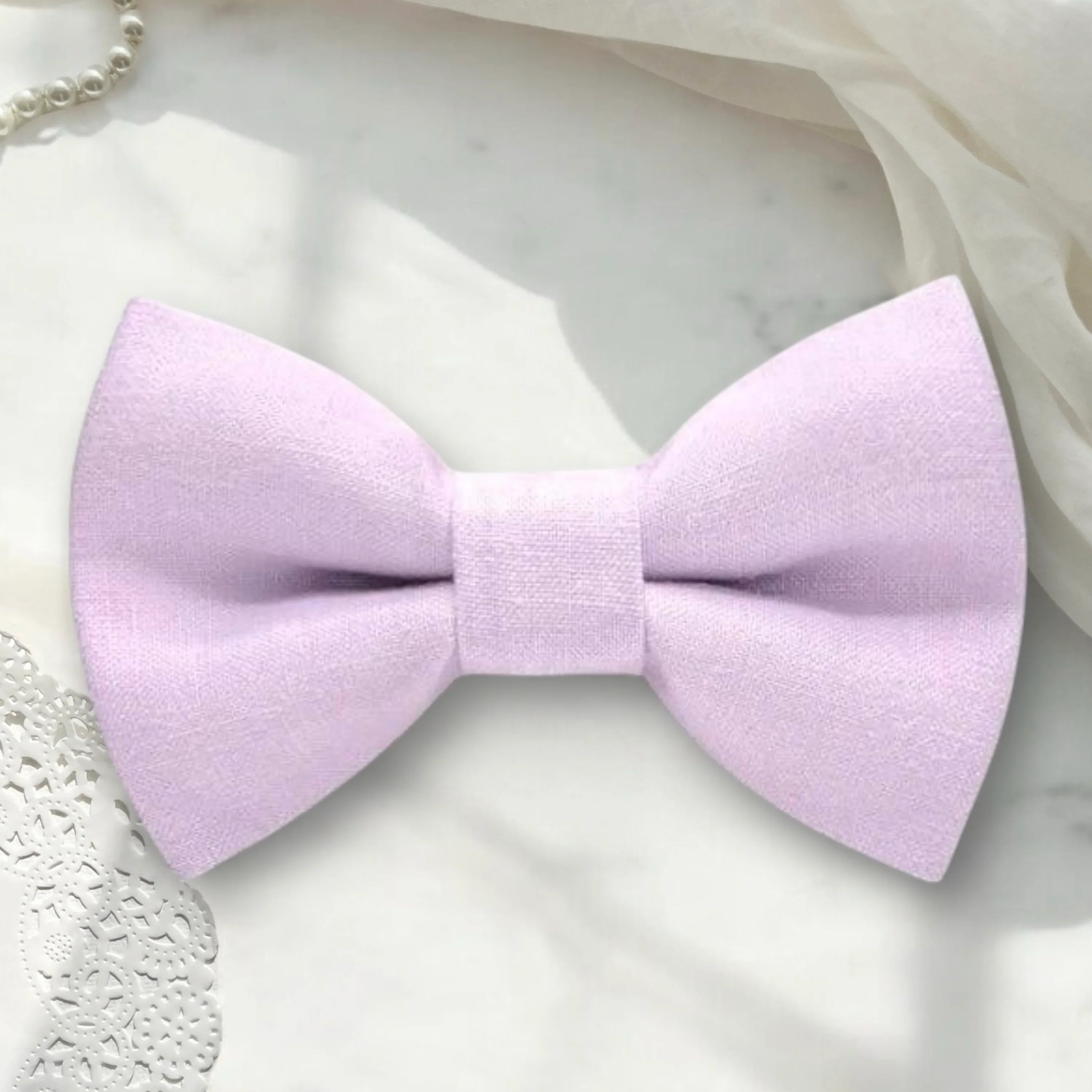 Size chart for pre-tied bow ties from The Bold Bow Tie detailing measurements across three sizes. Small is 3.5 inches wide and recommended for ages 6 months to 5 years. Medium is 4 inches wide and recommended for ages 6 to 12 years. Large is 4.5 inches wide and recommended for ages 13 years and up. Visual icons illustrate the relative sizes with horizontal arrows showing that width is measured from wingtip to wingtip. Bottom text notes that all bow ties are pre-tied and ready to add to your outfit.