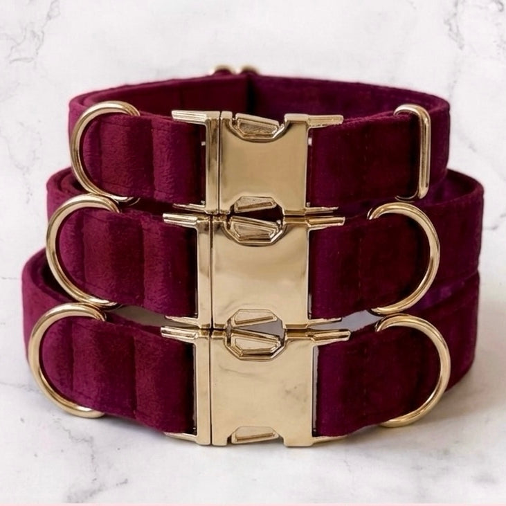 Burgundy dog collars with gold hardware on a marble background