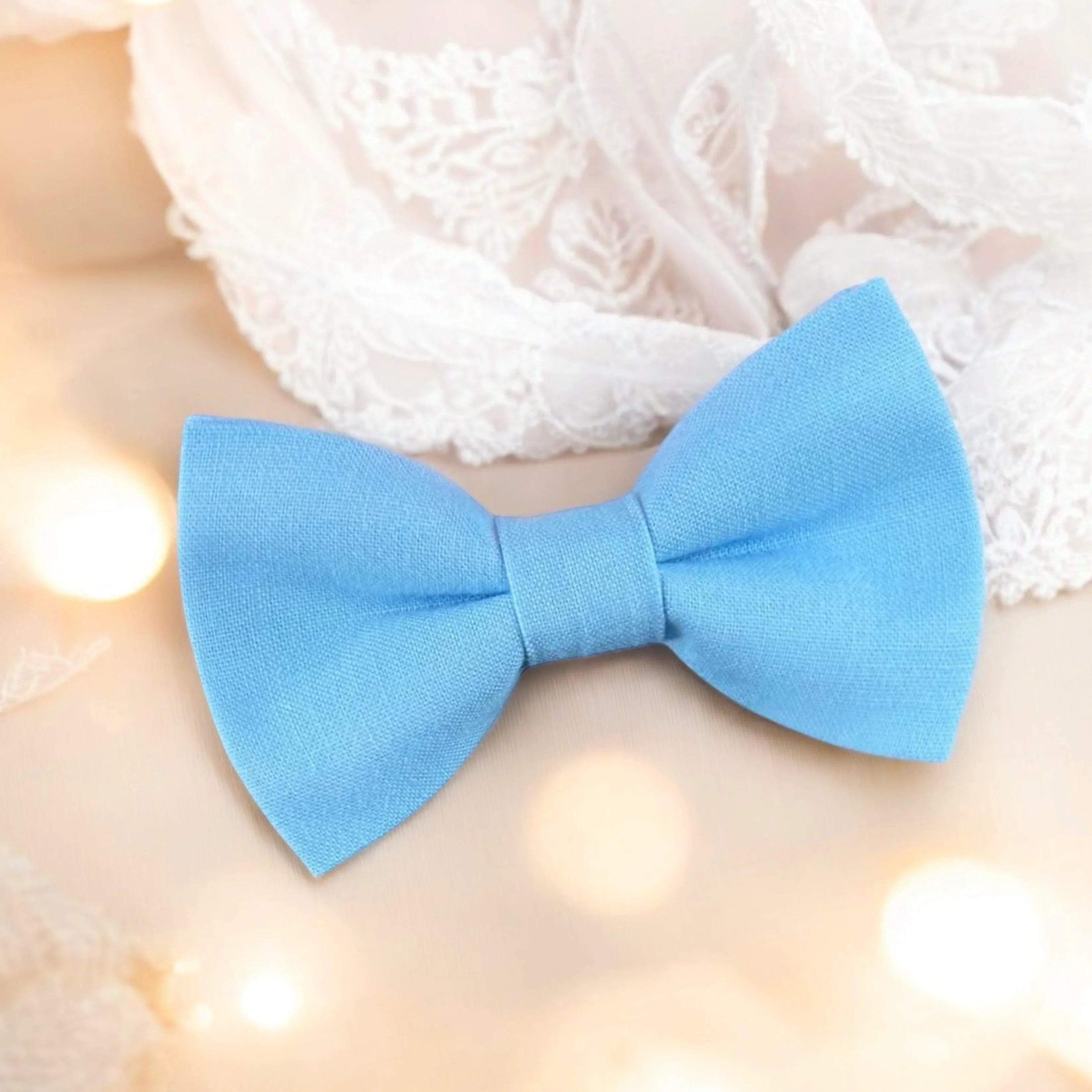 Size chart for pre-tied bow ties from The Bold Bow Tie detailing measurements across three sizes. Small is 3.5 inches wide and recommended for ages 6 months to 5 years. Medium is 4 inches wide and recommended for ages 6 to 12 years. Large is 4.5 inches wide and recommended for ages 13 years and up. Visual icons illustrate the relative sizes with horizontal arrows showing that width is measured from wingtip to wingtip. Bottom text notes that all bow ties are pre-tied and ready to add to your outfit.
