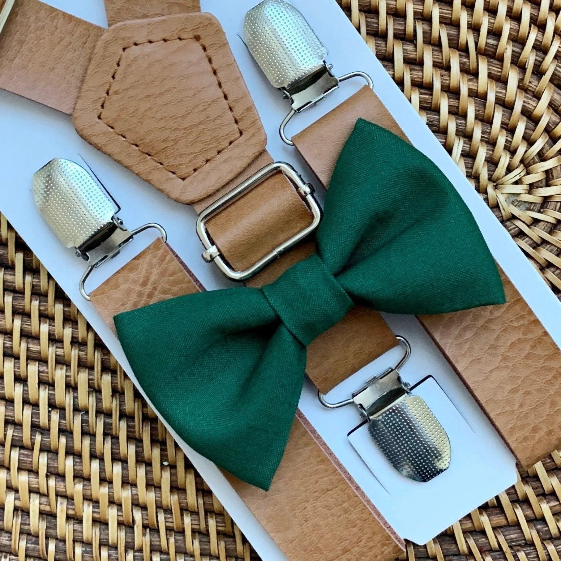 Green bow tie with brown suspenders on a woven surface