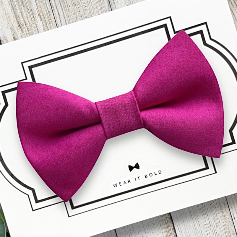 Hot pink dog bow tie on a white card with text on a wooden surface