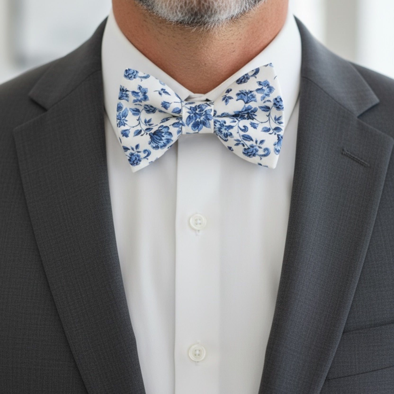 Groomsman wearing a gray suit with a blue and white floral bow tie at a wedding.