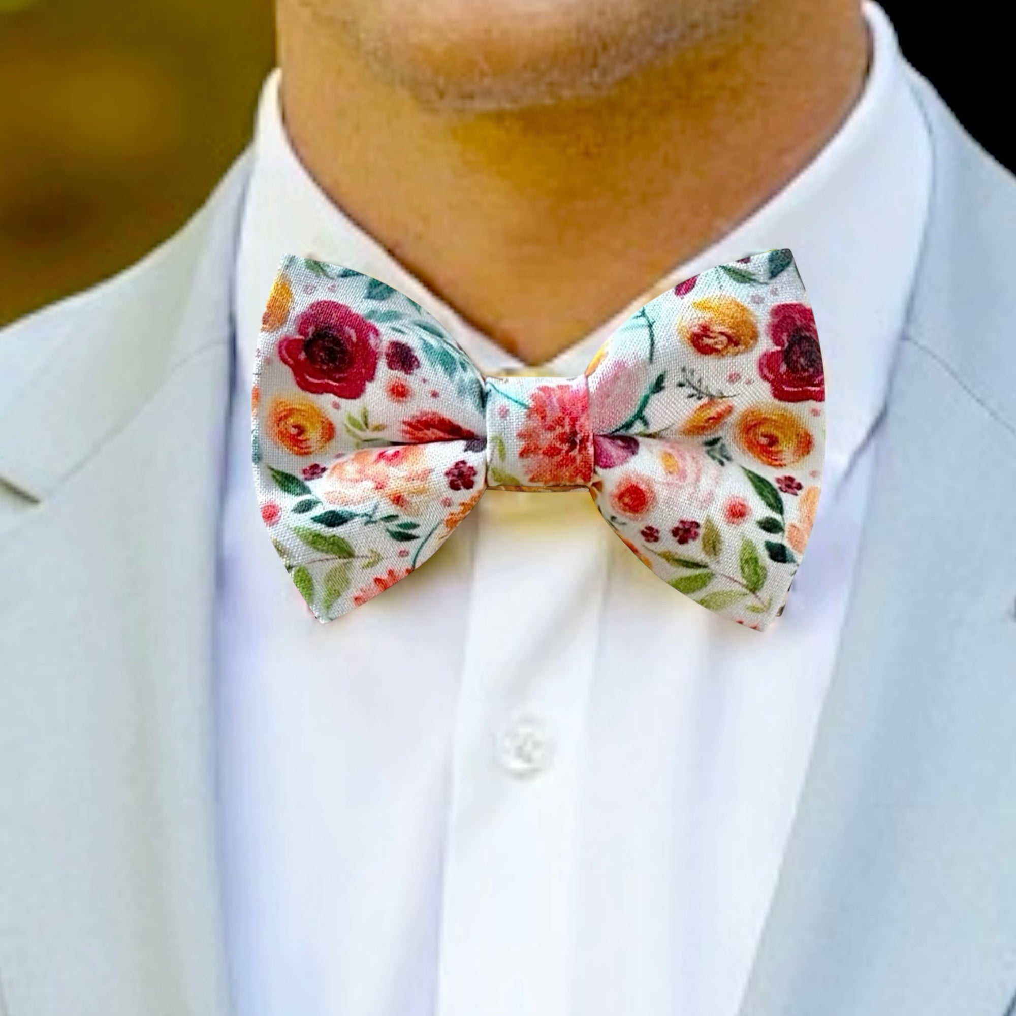 Floral bow tie worn by a person in a light gray suit and white shirt.