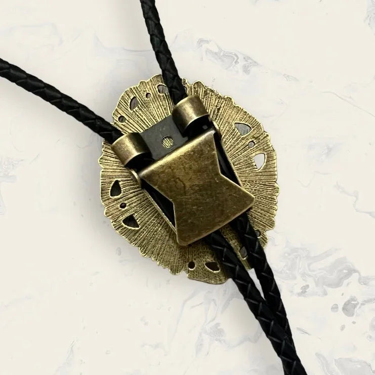 Bolo tie size chart from The Bold Bow Tie. The image displays a braided leather bolo tie with a round silver concho-style slide and silver metal tips, set against a multi-colored striped fabric background. A vertical dotted arrow on the right spans the full length of the piece, accompanied by text indicating a 39 inch cord length.