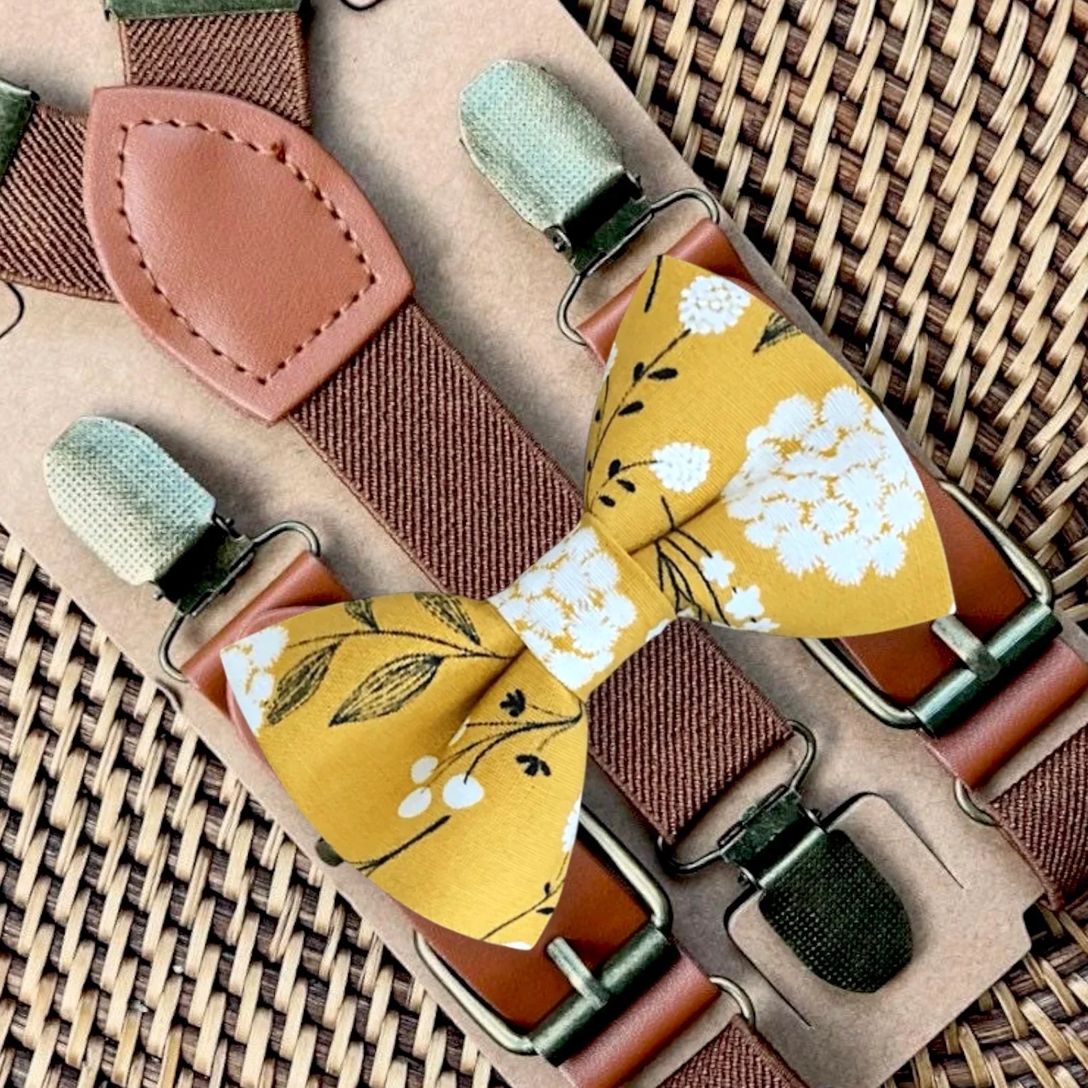 Mustard yellow Bow tie with floral pattern and suspenders on a woven surface
