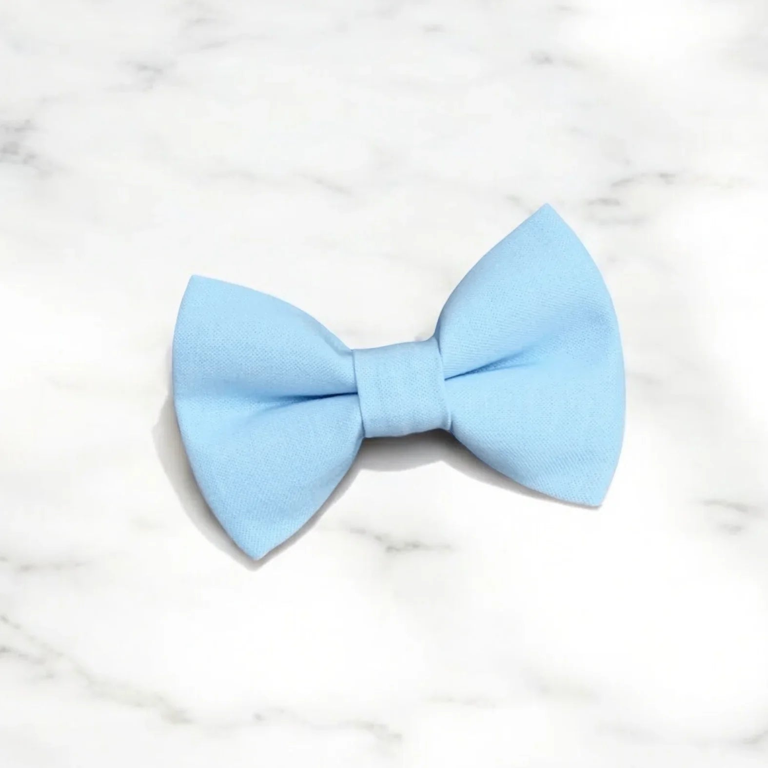 Size chart for pre-tied bow ties from The Bold Bow Tie detailing measurements across three sizes. Small is 3.5 inches wide and recommended for ages 6 months to 5 years. Medium is 4 inches wide and recommended for ages 6 to 12 years. Large is 4.5 inches wide and recommended for ages 13 years and up. Visual icons illustrate the relative sizes with horizontal arrows showing that width is measured from wingtip to wingtip. Bottom text notes that all bow ties are pre-tied and ready to add to your outfit.