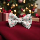 Christmas-themed bow tie with Santa Claus pattern on a red surface with blurred festive background