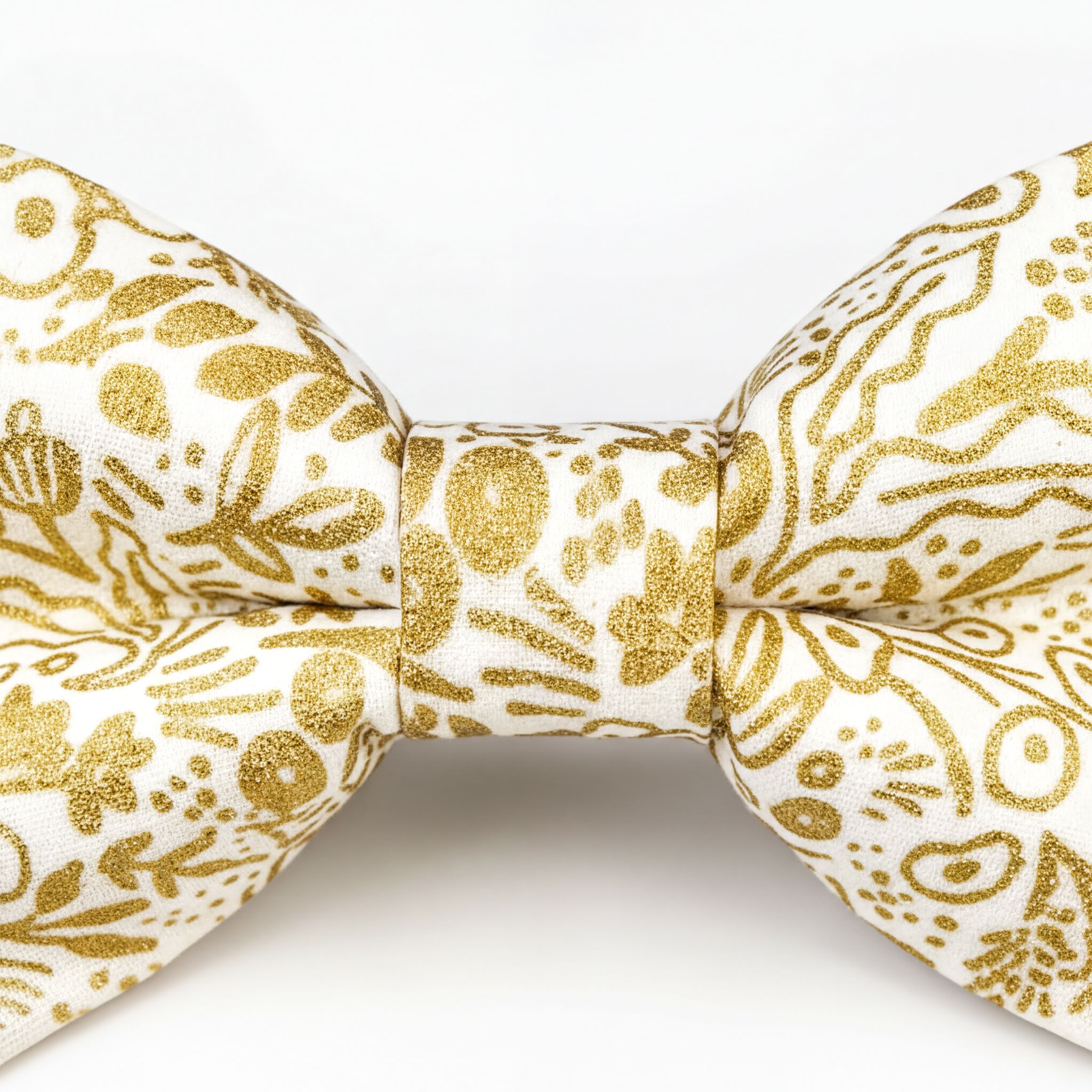 A close-up view of a gold and white bow tie with a floral pattern.