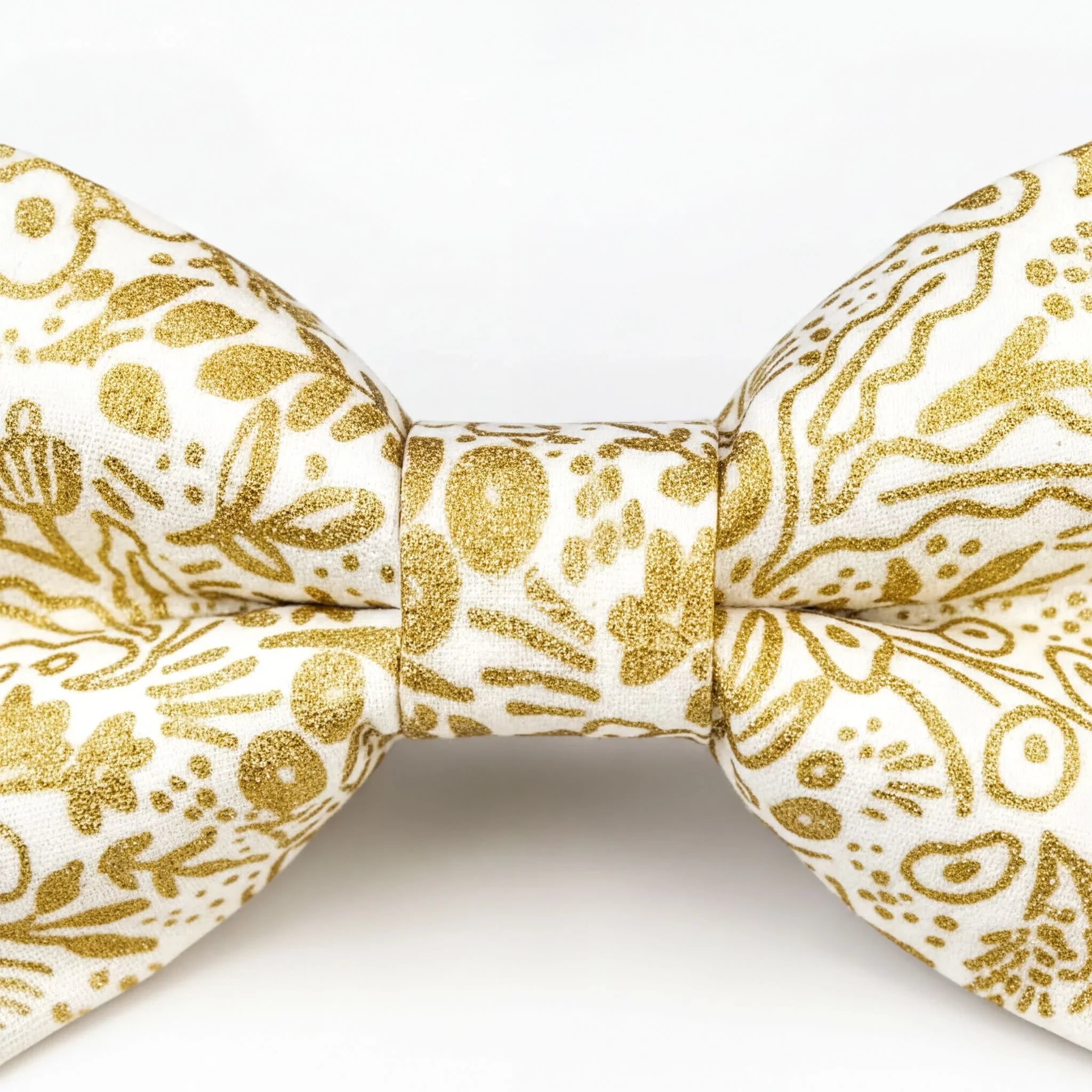 A close-up view of a gold and white bow tie with a floral pattern.