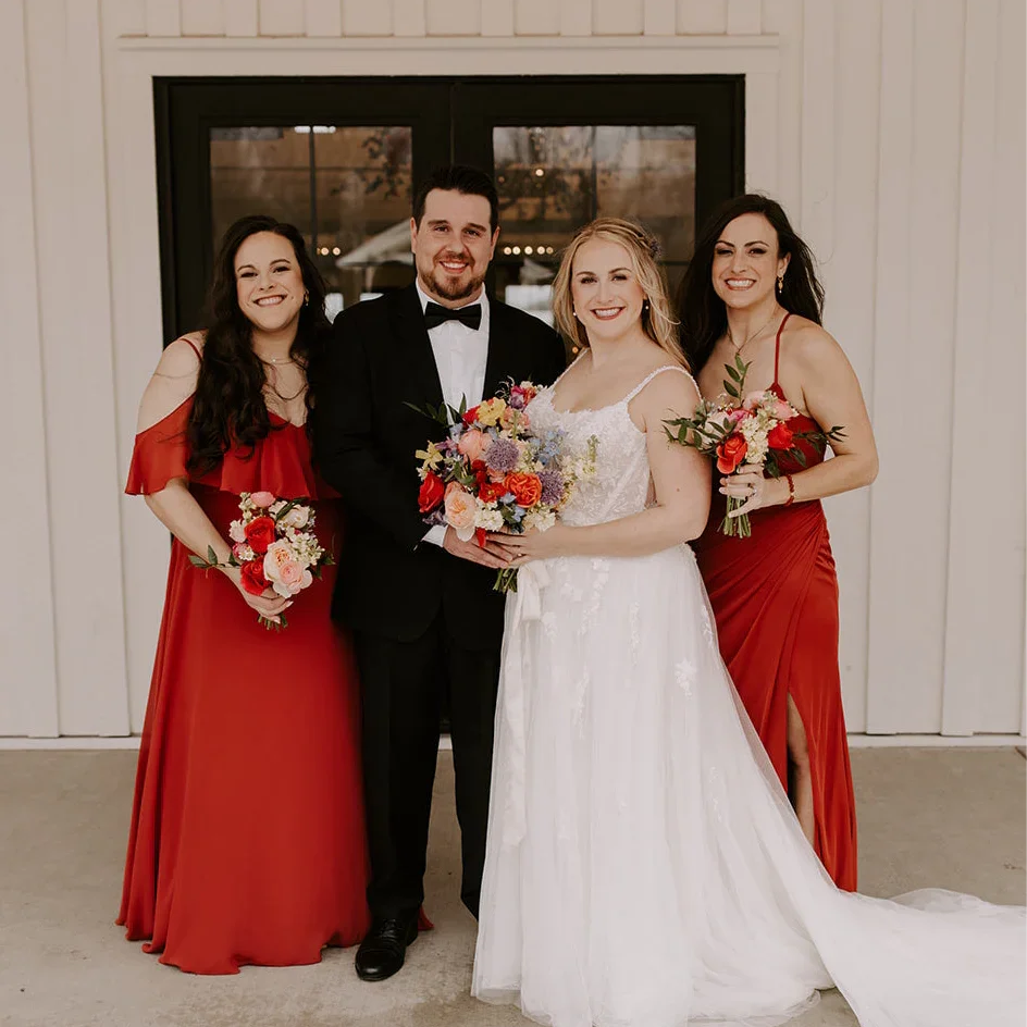Satin black bow tie for weddings, groomsmen, and ring bearers being worn by groom with his bride and two bridesmaids.