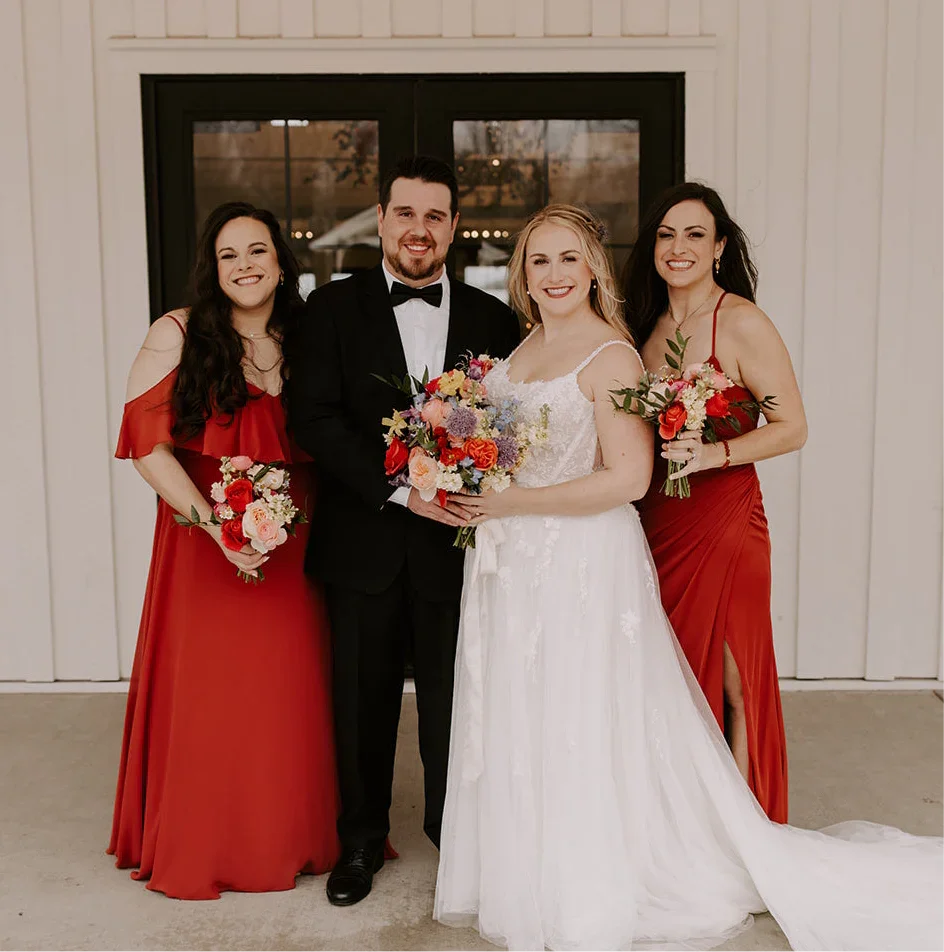 Satin black bow tie for weddings, groomsmen, and ring bearers being worn by groom with his bride and two bridesmaids.