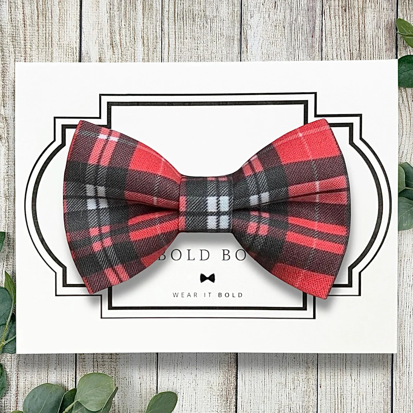 Plaid dog bow tie in red and black on a wood table.