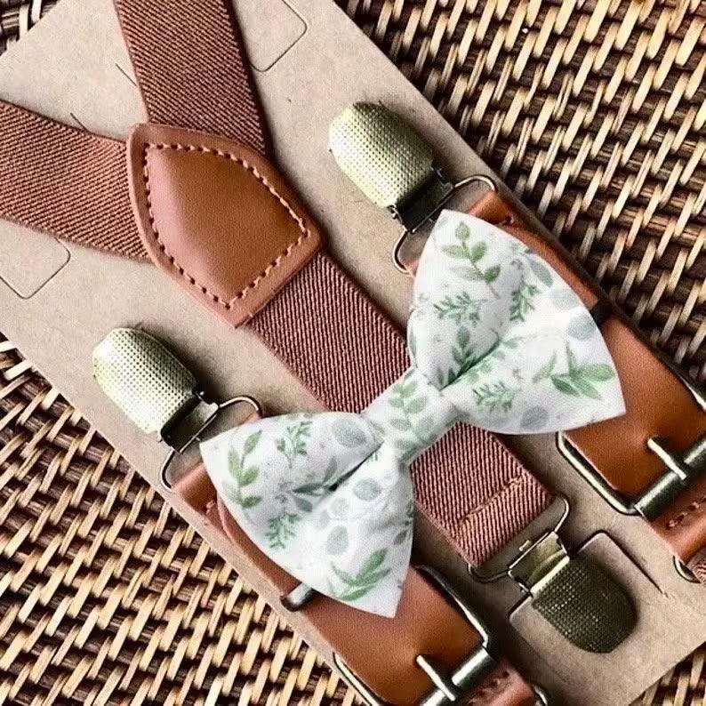 Sage floral bow tie paired with white and cognac buckle suspenders on a woven background