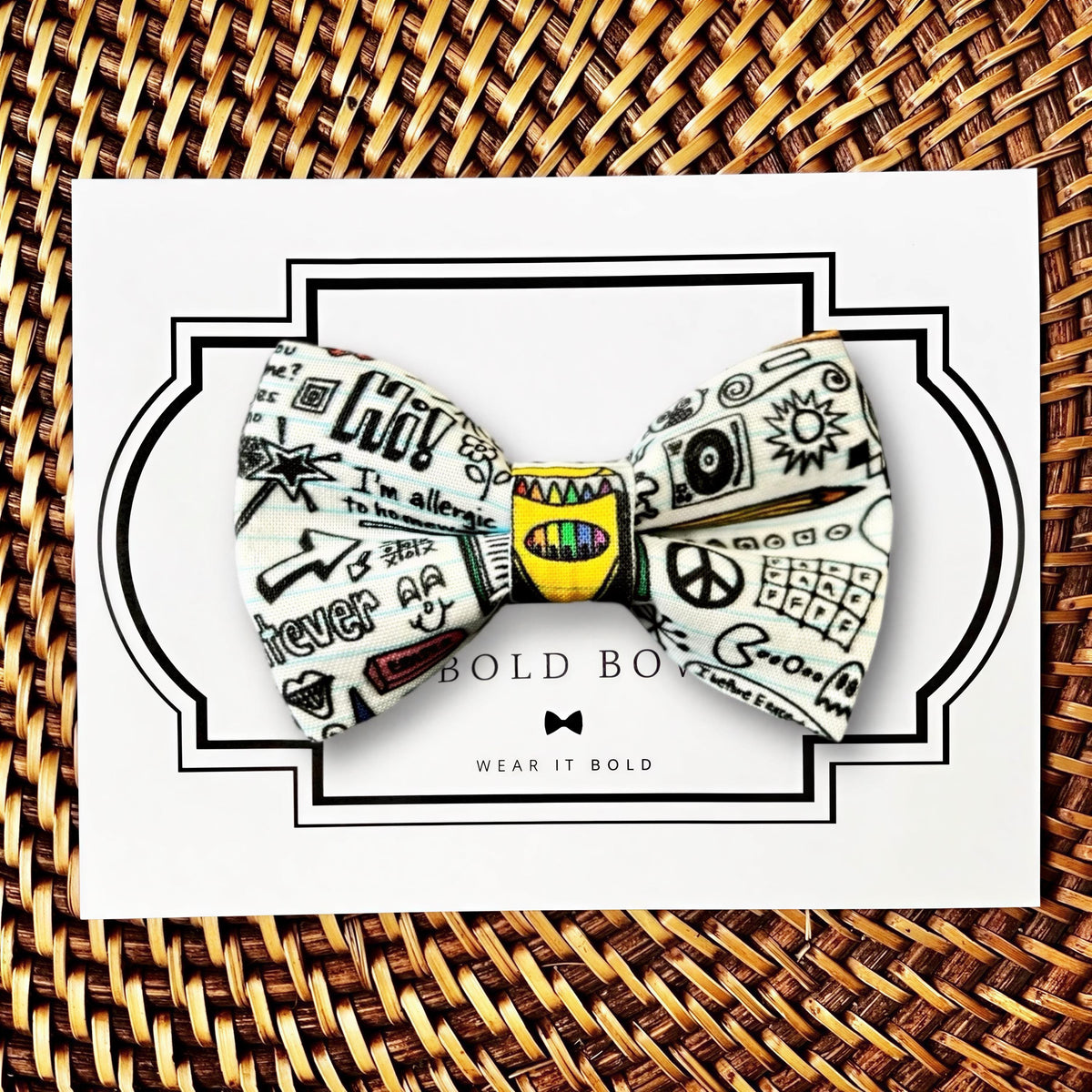 A colorful bow tie with various doodles and text printed on it, displayed on a white card with a wicker border.
