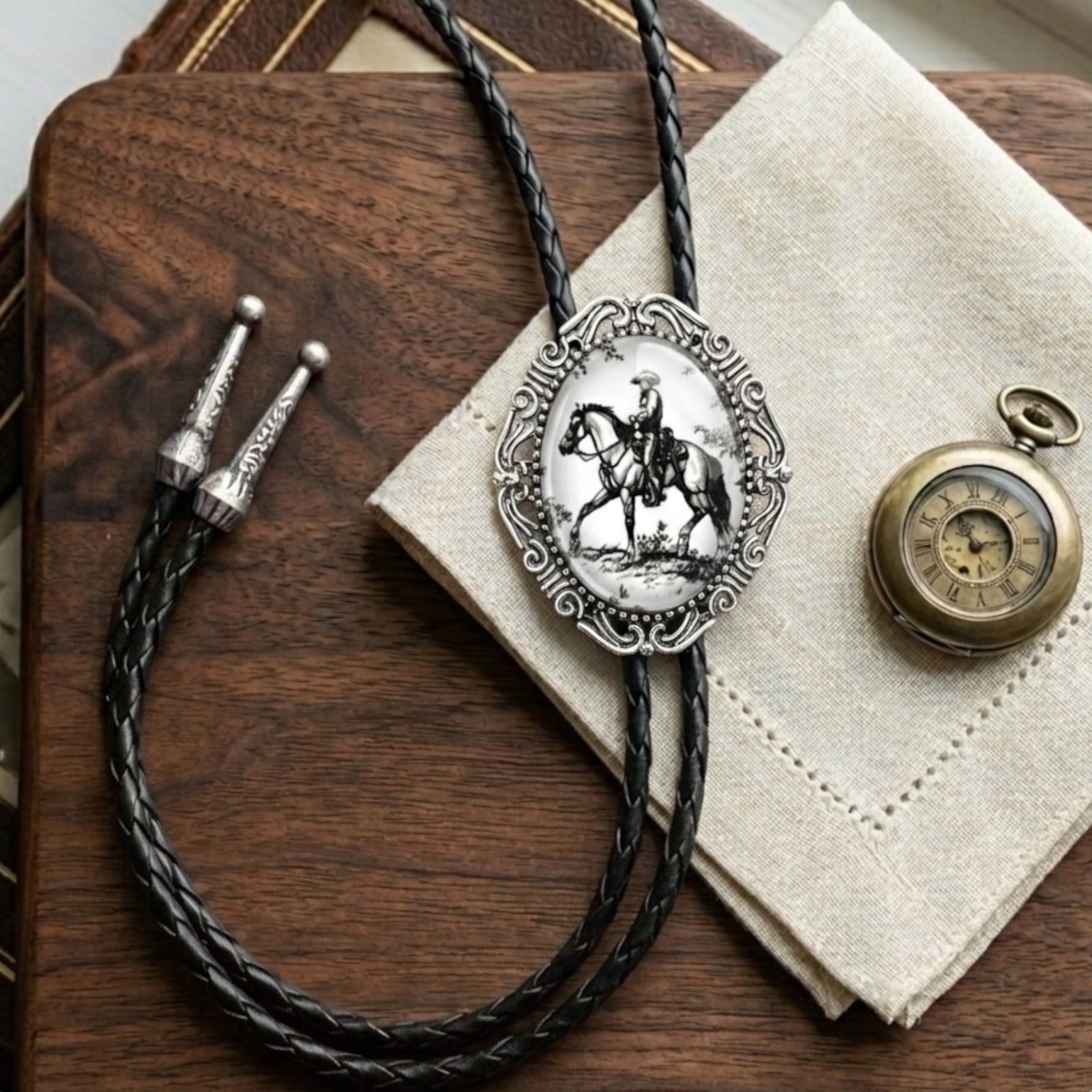 Bolo tie for men with horse design pendant on a wooden surface with a pocket watch.