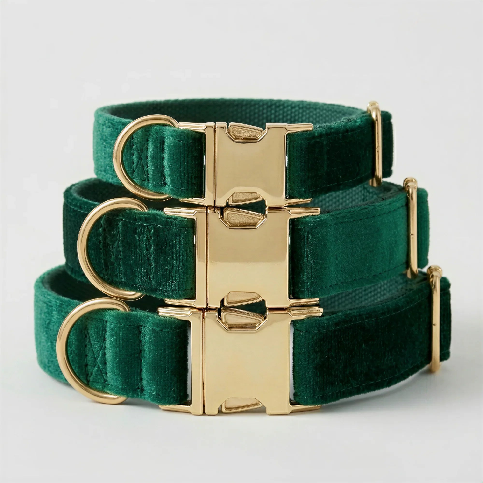 Green velvet dog collars with gold buckles on a light gray background