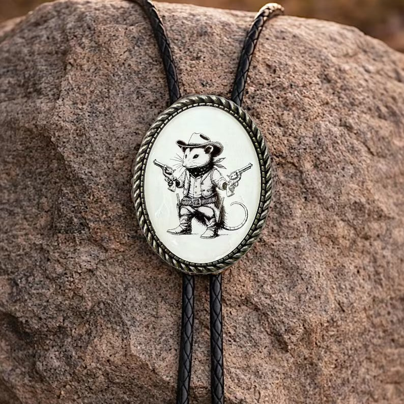 Opossum bolo tie with cowboy design on a rock.