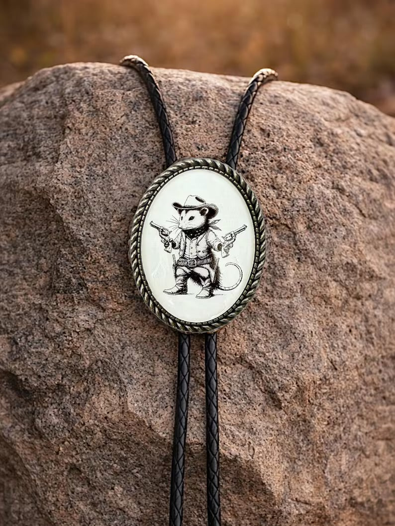 Opossum bolo tie with cowboy design on a rock.