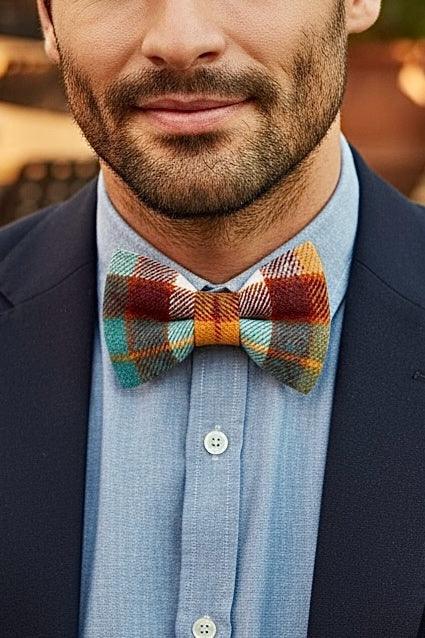Plaid bow tie in orange blue and white worn by a man in a suit.