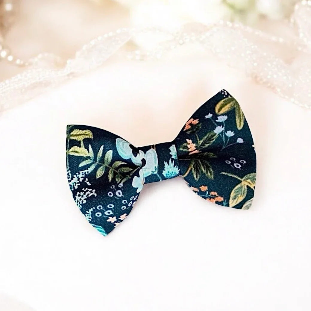 Size chart for pre-tied bow ties from The Bold Bow Tie detailing measurements across three sizes. Small is 3.5 inches wide and recommended for ages 6 months to 5 years. Medium is 4 inches wide and recommended for ages 6 to 12 years. Large is 4.5 inches wide and recommended for ages 13 years and up. Visual icons illustrate the relative sizes with horizontal arrows showing that width is measured from wingtip to wingtip. Bottom text notes that all bow ties are pre-tied and ready to add to your outfit.