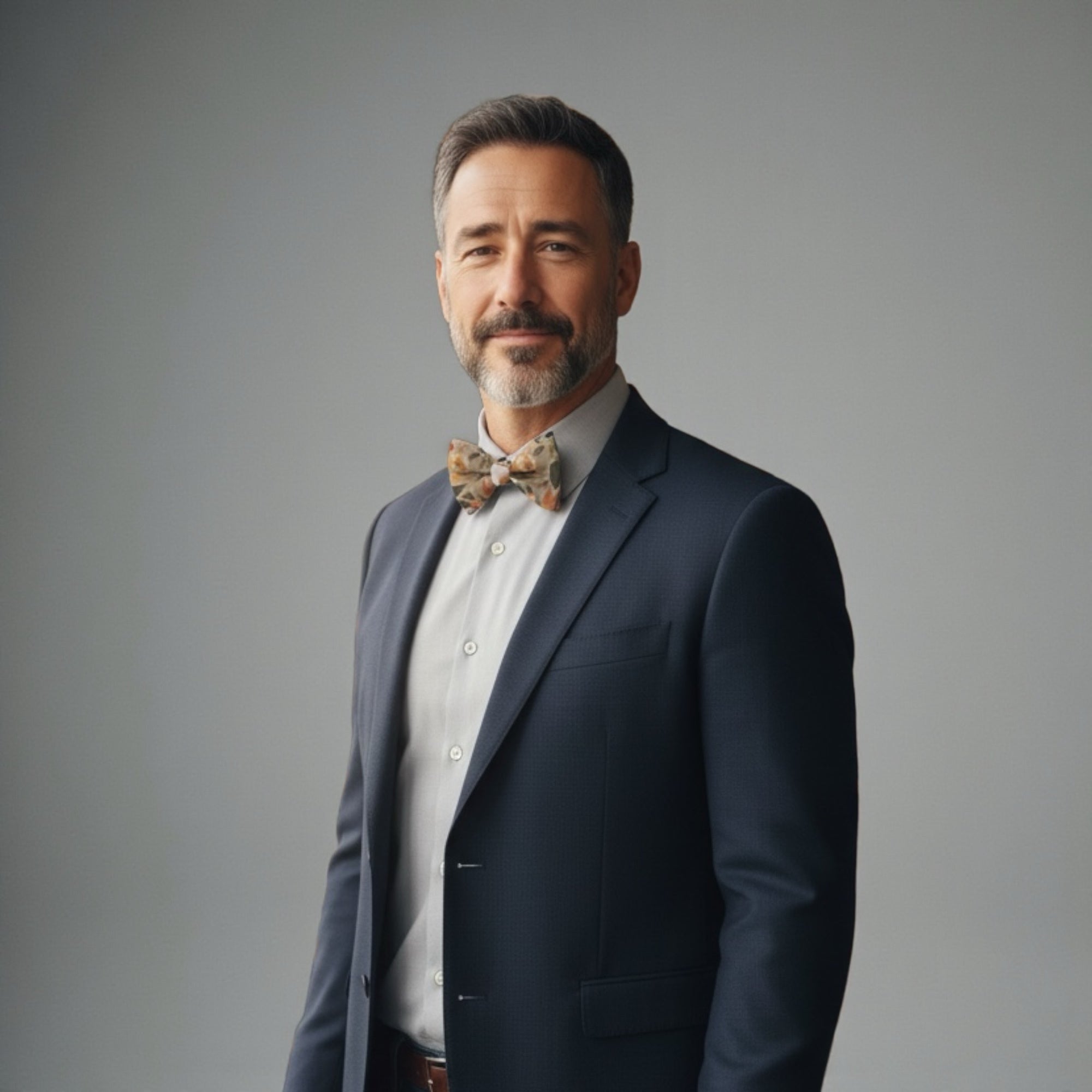 Man wearing a taupe floral bow tie with accents of terracotta and burnt orange for a wedding.