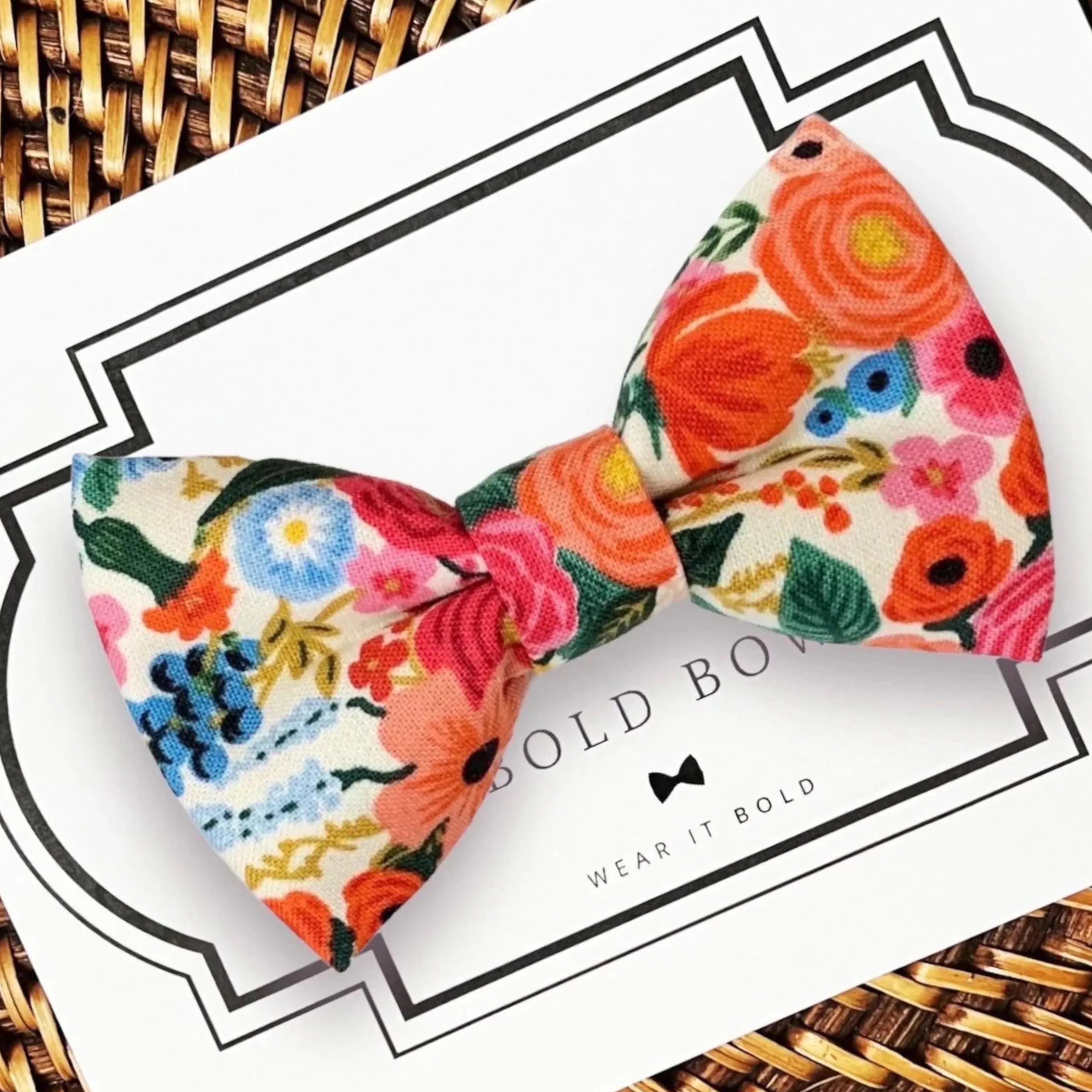 Bright floral bow tie for dogs or cats displayed on a white card with Rifle Paper Co pattern