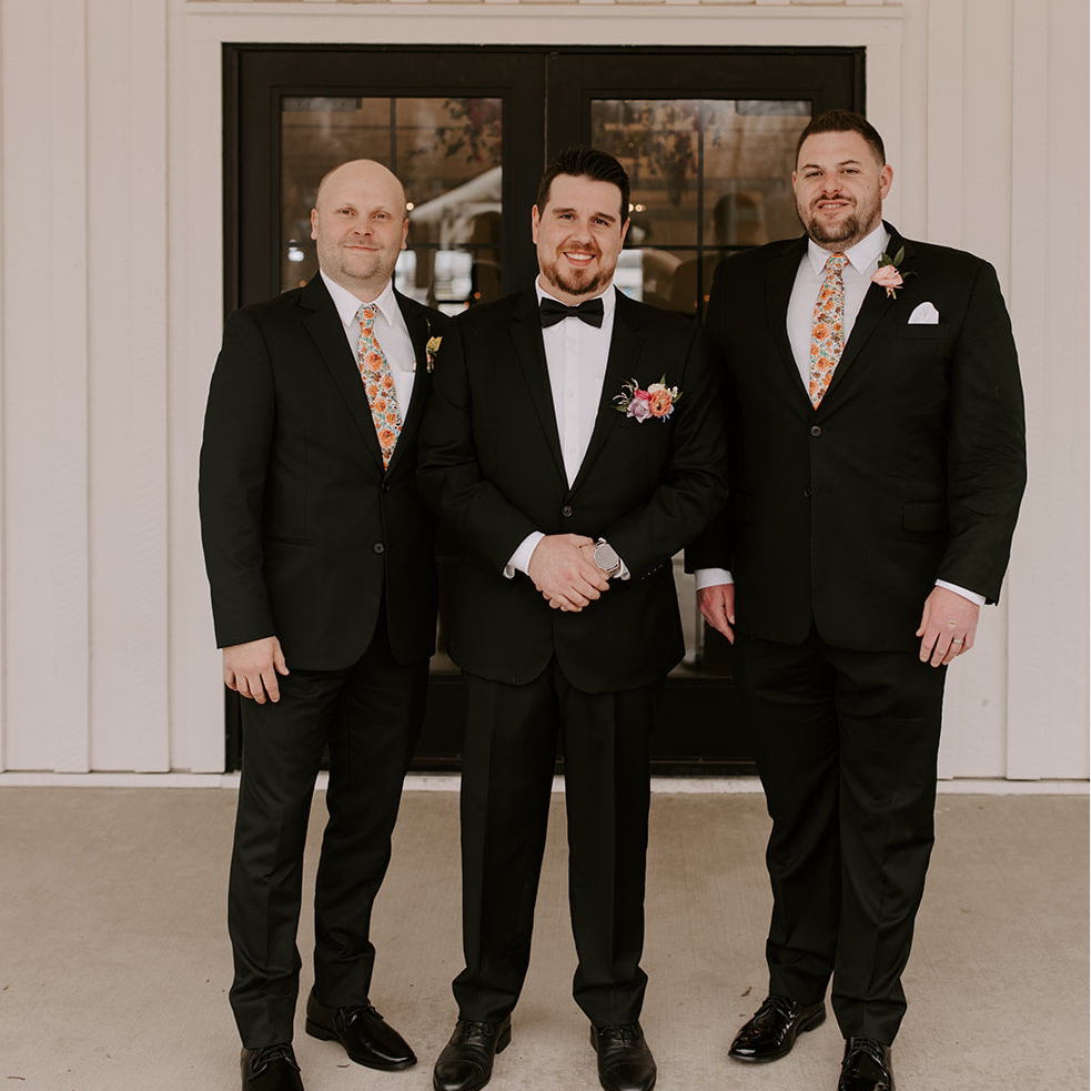 Groomsmen posing in burnt orange floral men’s ties for wedding.