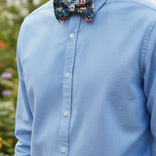 Floral bow tie for men worn by a man at an outdoor wedding.