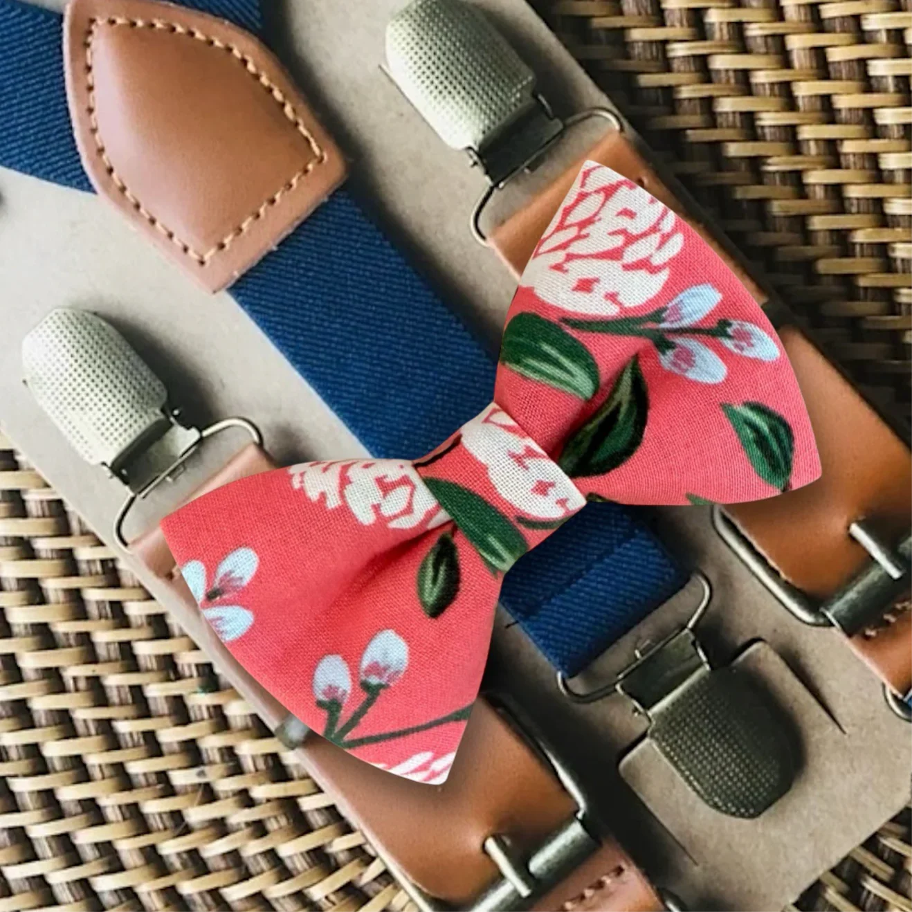 Pink Floral bow tie with suspenders on a woven surface