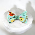 Blue and green floral men’s bow tie for weddings, groomsmen or ring bearers on a marble pedestal.