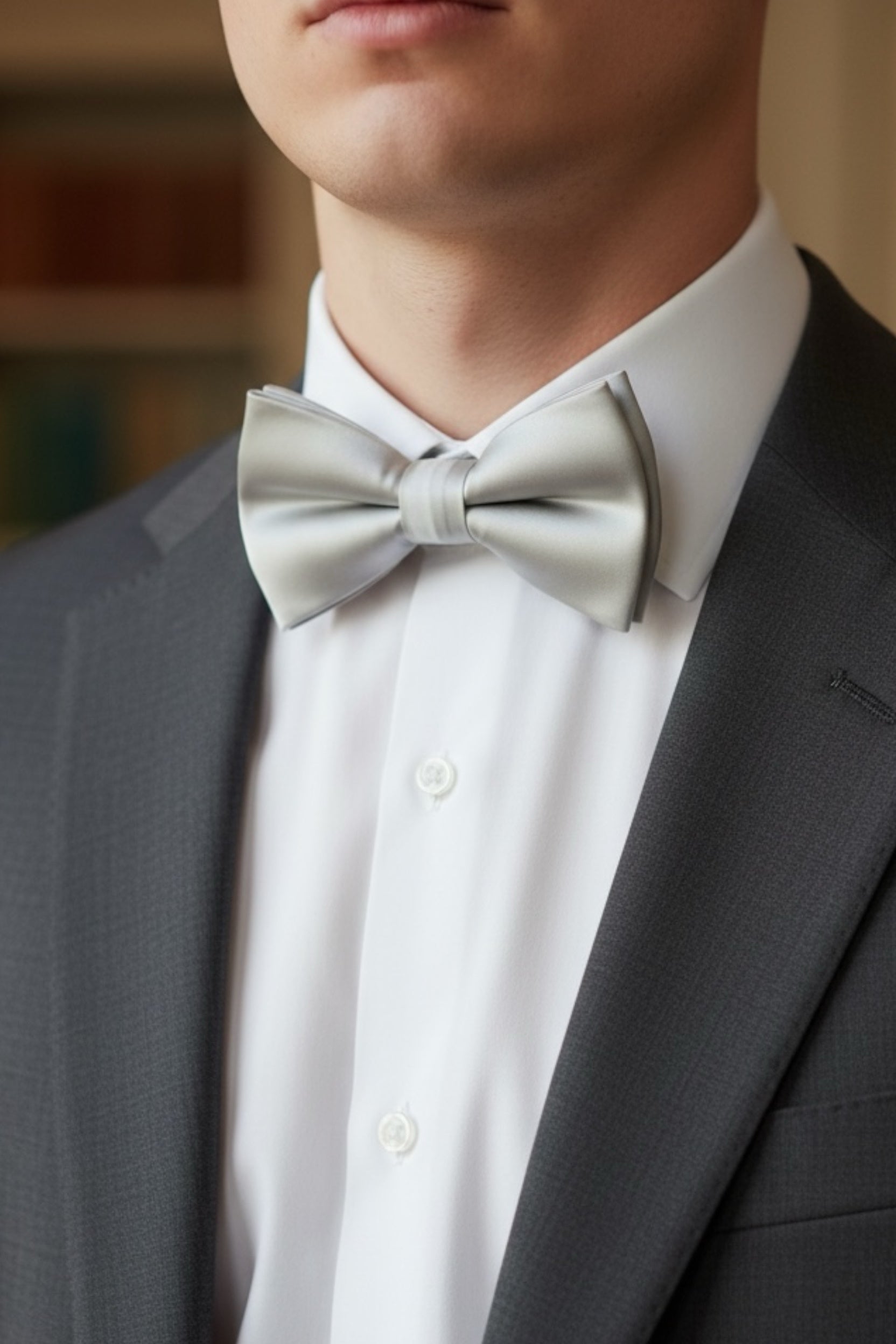 Man wearing a silver bow tie and gray suit jacket at a wedding.