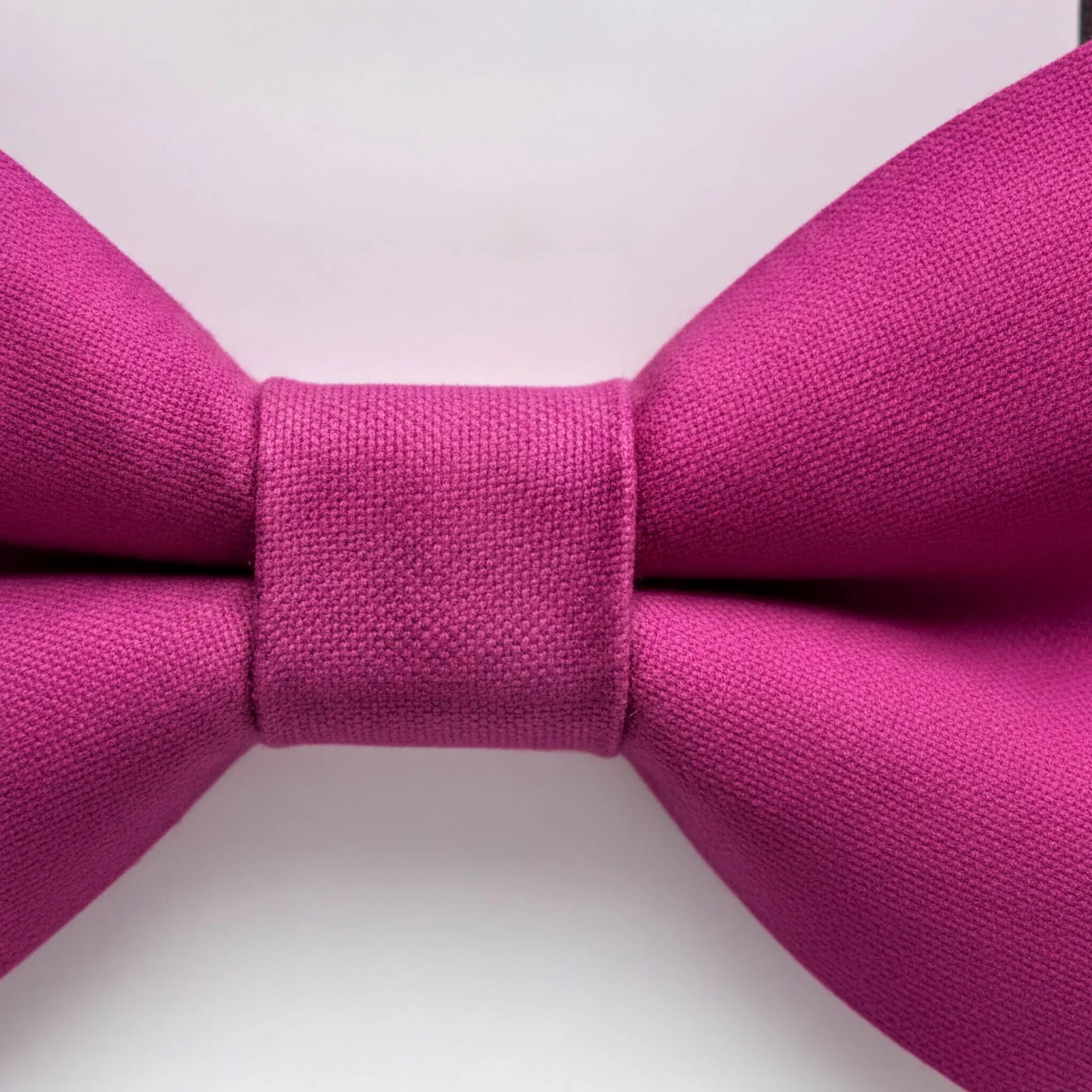 A close-up view of a vibrant pink bow tie against a plain white background.
