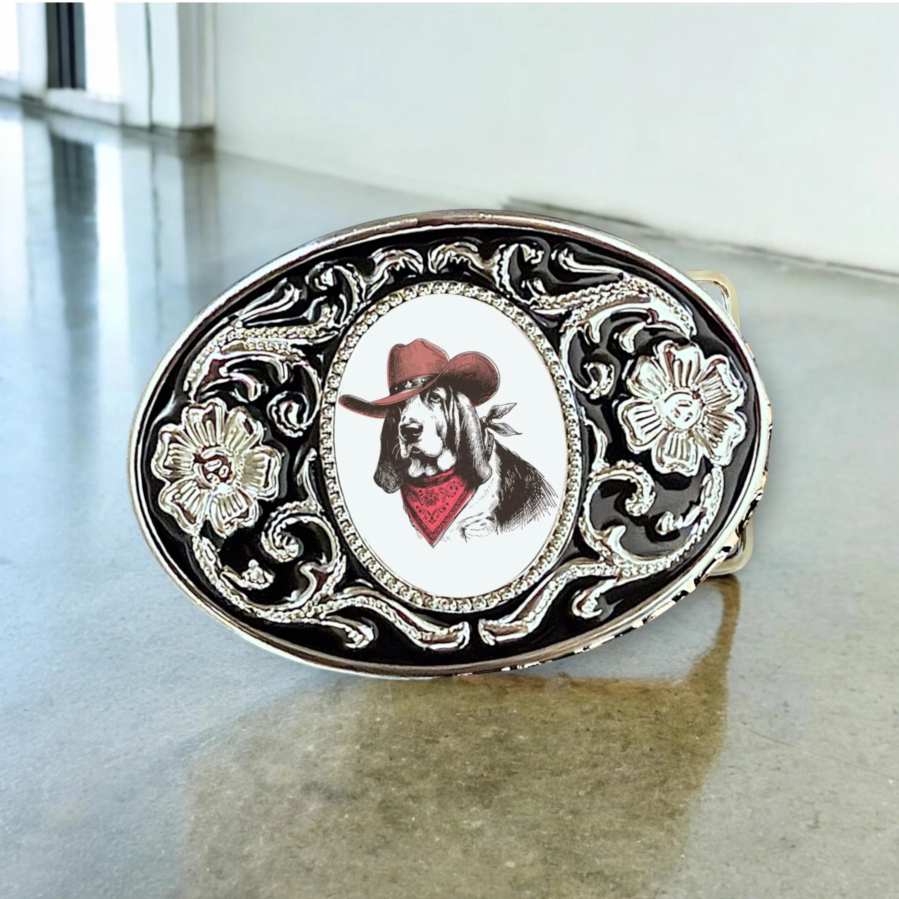 Belt buckle with a dog wearing a cowboy hat and bandana design on a reflective surface.