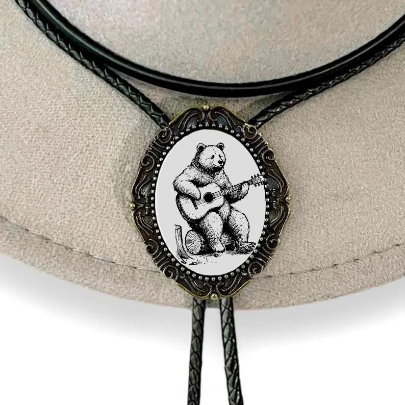 Bolo tie with bear playing guitar design on a beige background