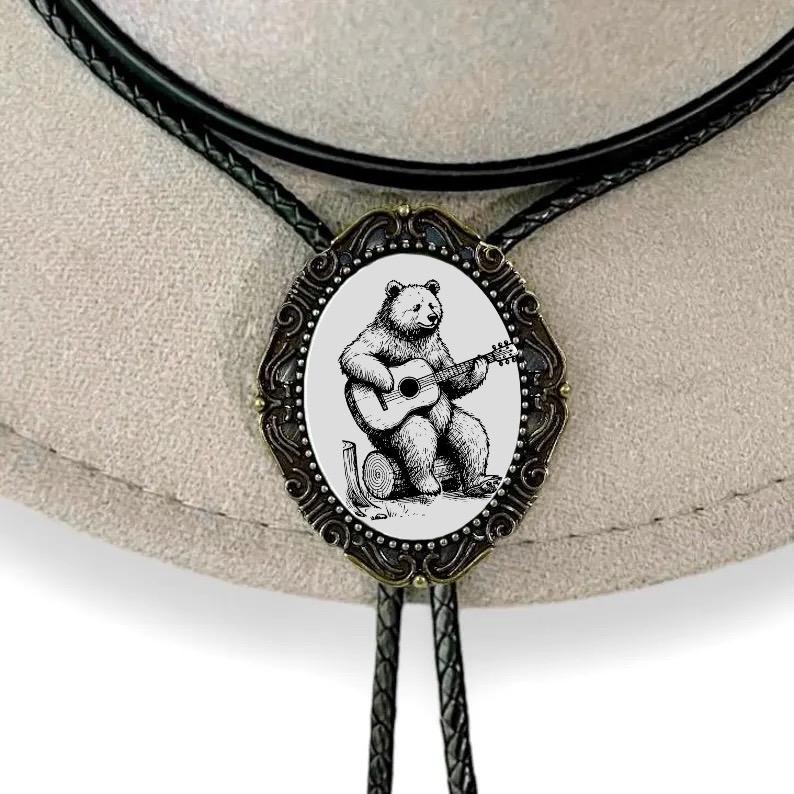 Bolo tie with bear playing guitar design on a beige background