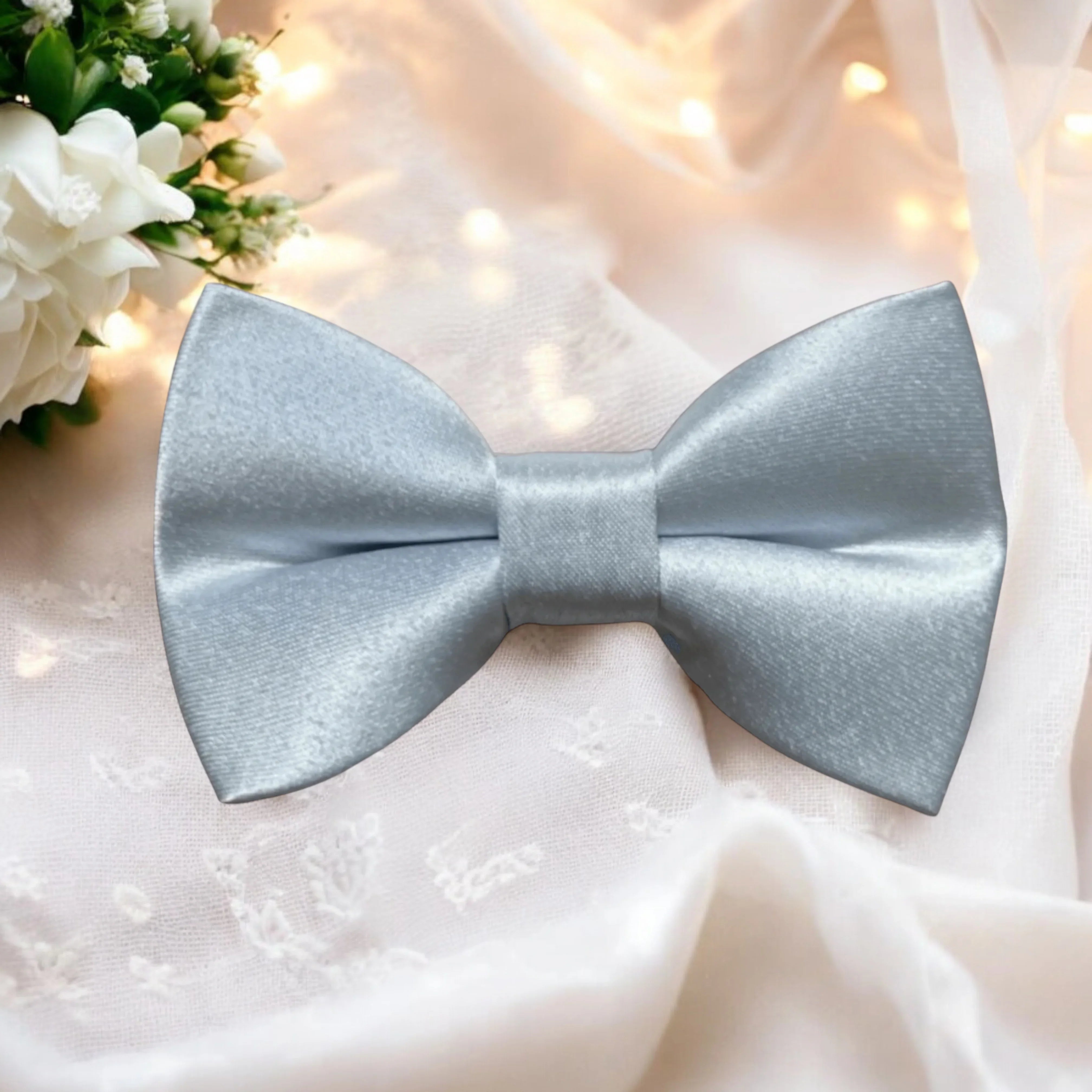 Size chart for pre-tied bow ties from The Bold Bow Tie detailing measurements across three sizes. Small is 3.5 inches wide and recommended for ages 6 months to 5 years. Medium is 4 inches wide and recommended for ages 6 to 12 years. Large is 4.5 inches wide and recommended for ages 13 years and up. Visual icons illustrate the relative sizes with horizontal arrows showing that width is measured from wingtip to wingtip. Bottom text notes that all bow ties are pre-tied and ready to add to your outfit.