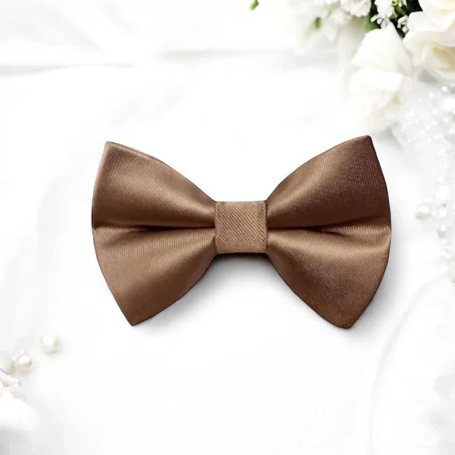 Size chart for pre-tied bow ties from The Bold Bow Tie detailing measurements across three sizes. Small is 3.5 inches wide and recommended for ages 6 months to 5 years. Medium is 4 inches wide and recommended for ages 6 to 12 years. Large is 4.5 inches wide and recommended for ages 13 years and up. Visual icons illustrate the relative sizes with horizontal arrows showing that width is measured from wingtip to wingtip. Bottom text notes that all bow ties are pre-tied and ready to add to your outfit.
